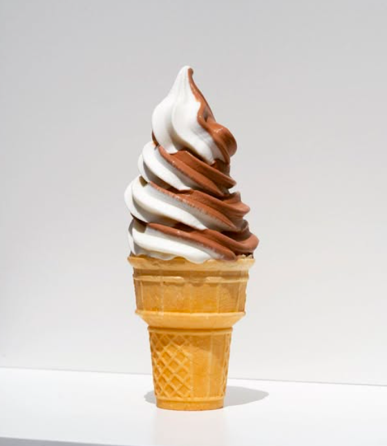 Swirl of vanilla and chocolate soft serve ice cream in a cone.