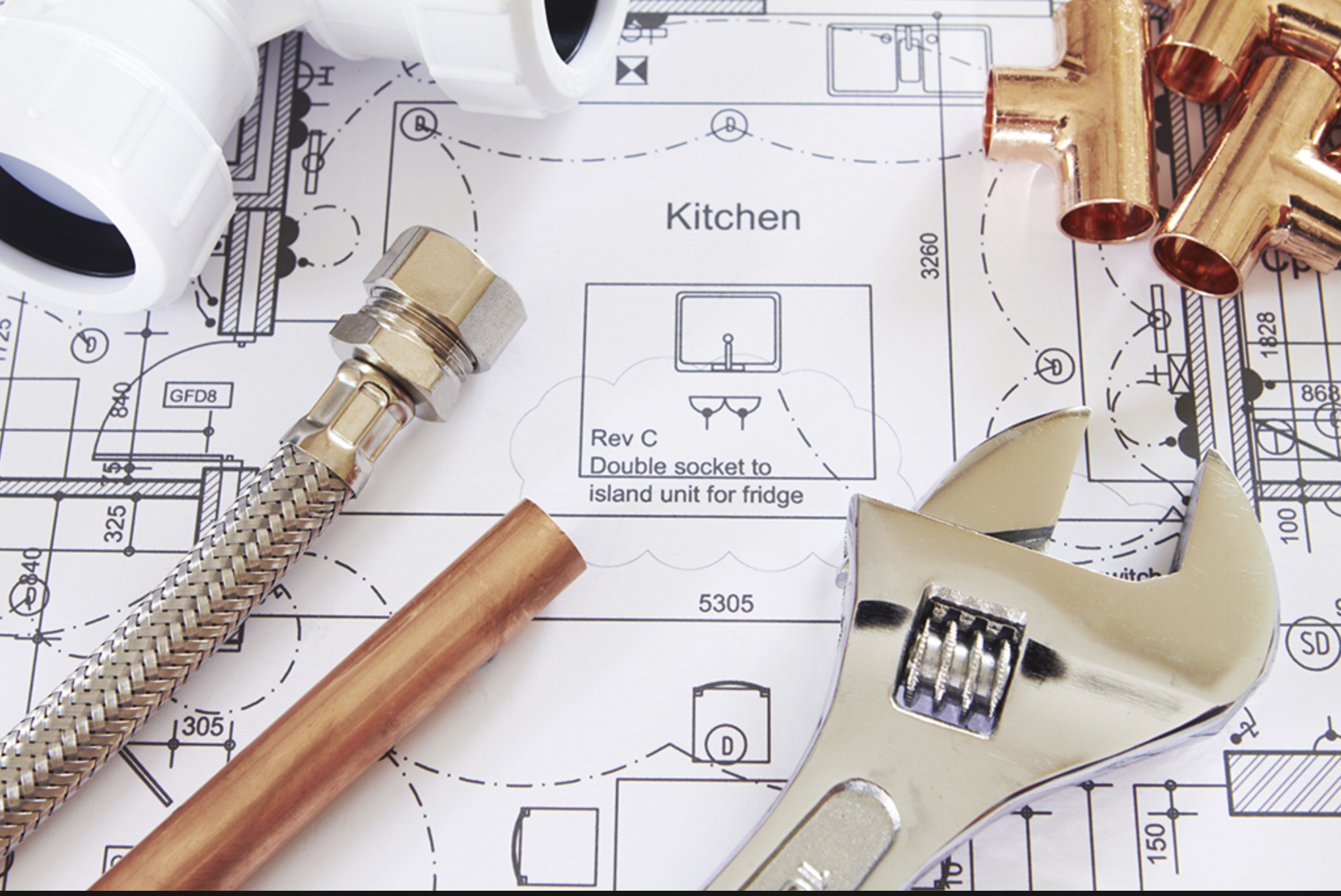Plumbing tools and copper pipes on a kitchen plumbing blueprint.