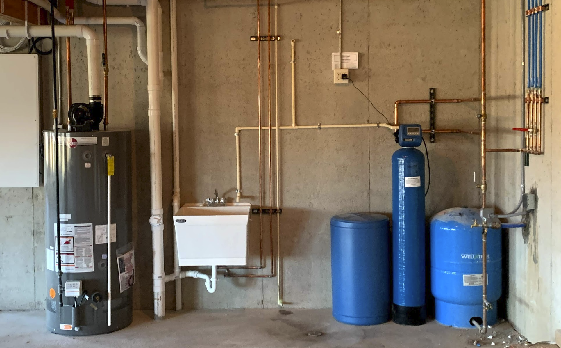 Water heater, water softener, and plumbing system with pipes and valves in a utility room.