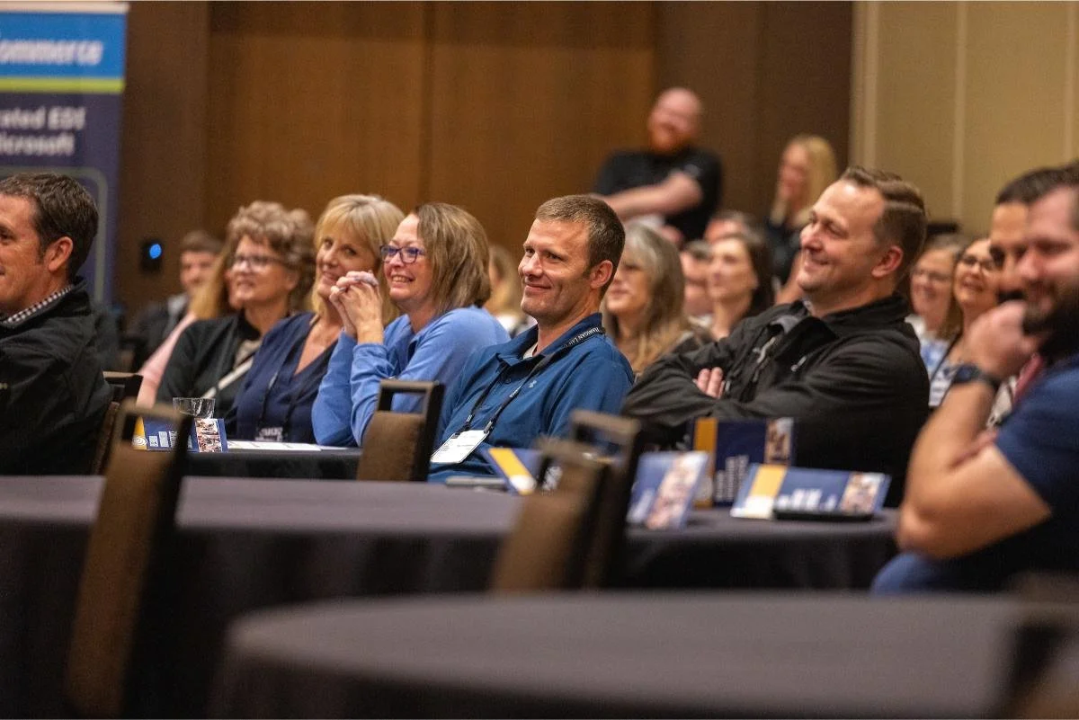 People sitting in an audience and listening to a presentation or speech, smiling and enjoying the event.