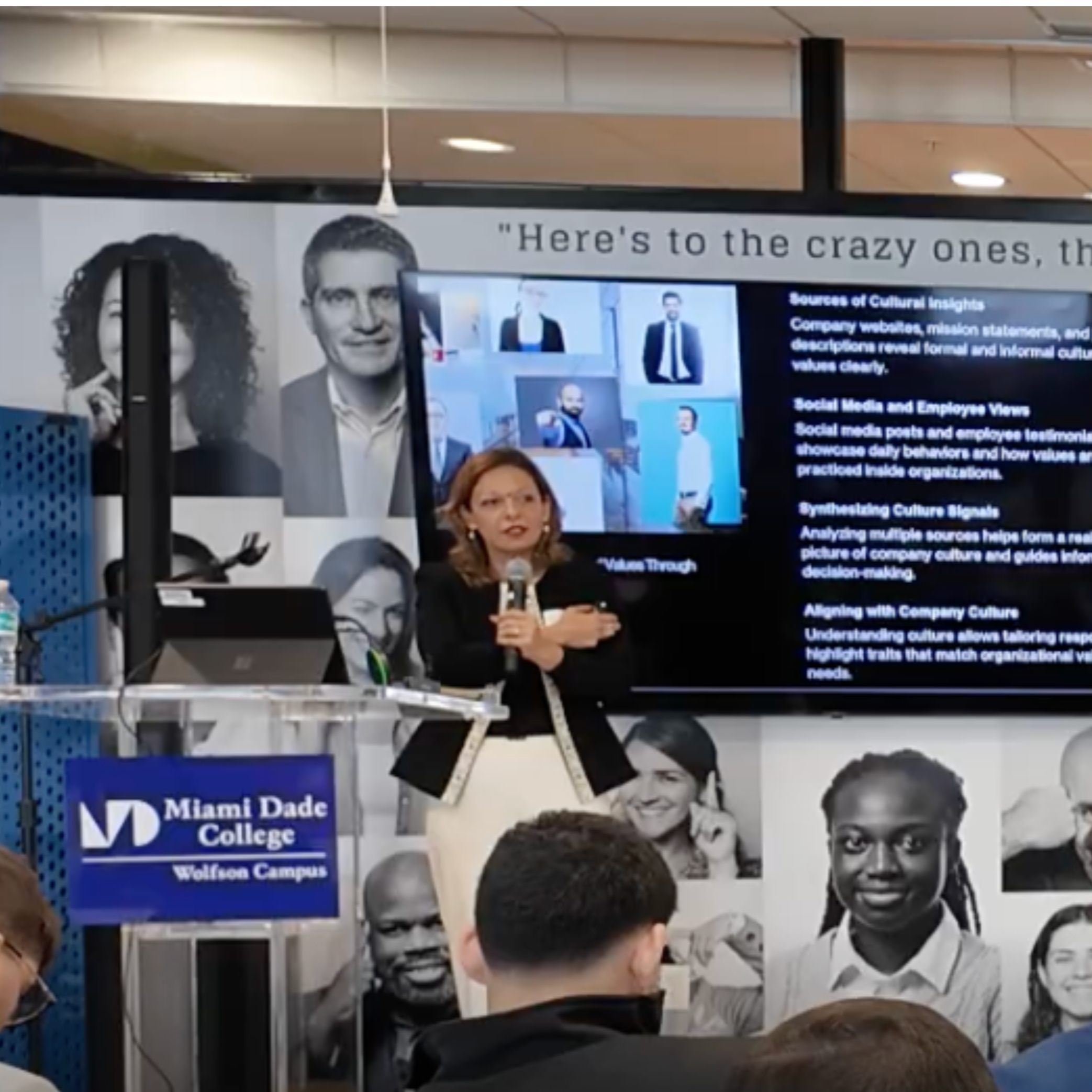 A display board at Miami Dade College Wolfson Campus with images of diverse individuals and information about company culture, emphasizing the importance of understanding culture and employee behavior in organizational decision-making.