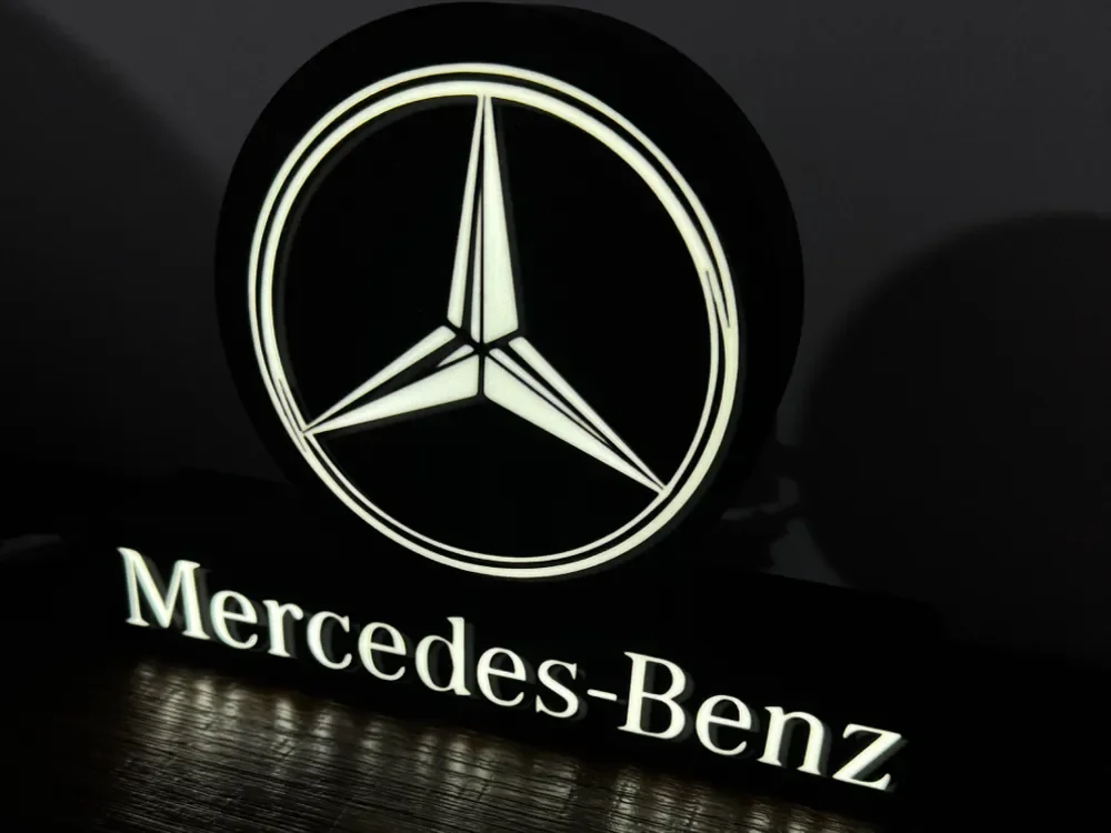 Illuminated Mercedes-Benz logo and text on a black background.