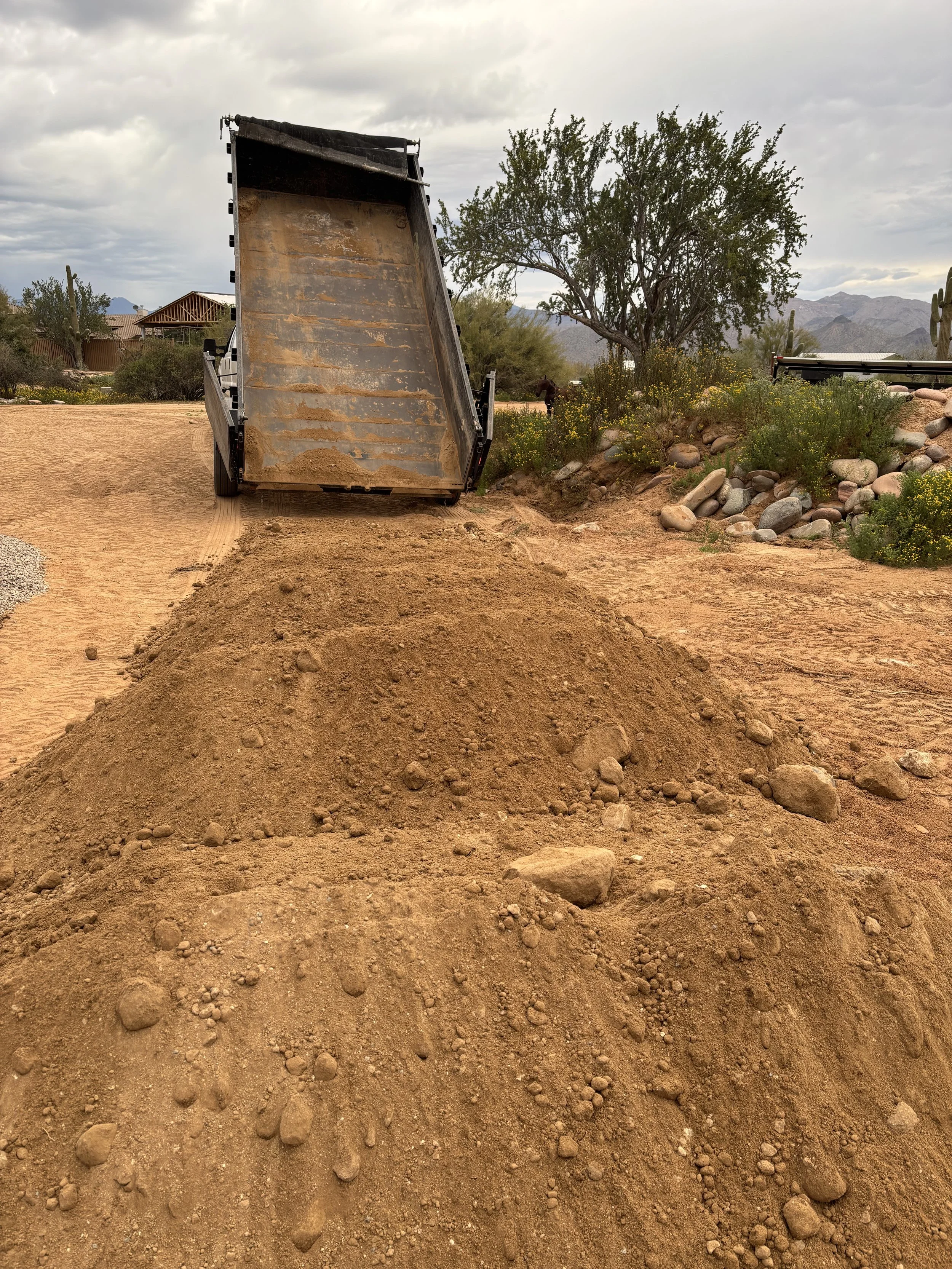 Dump truck unloading sand on a road with mountains in the background in Phoenix