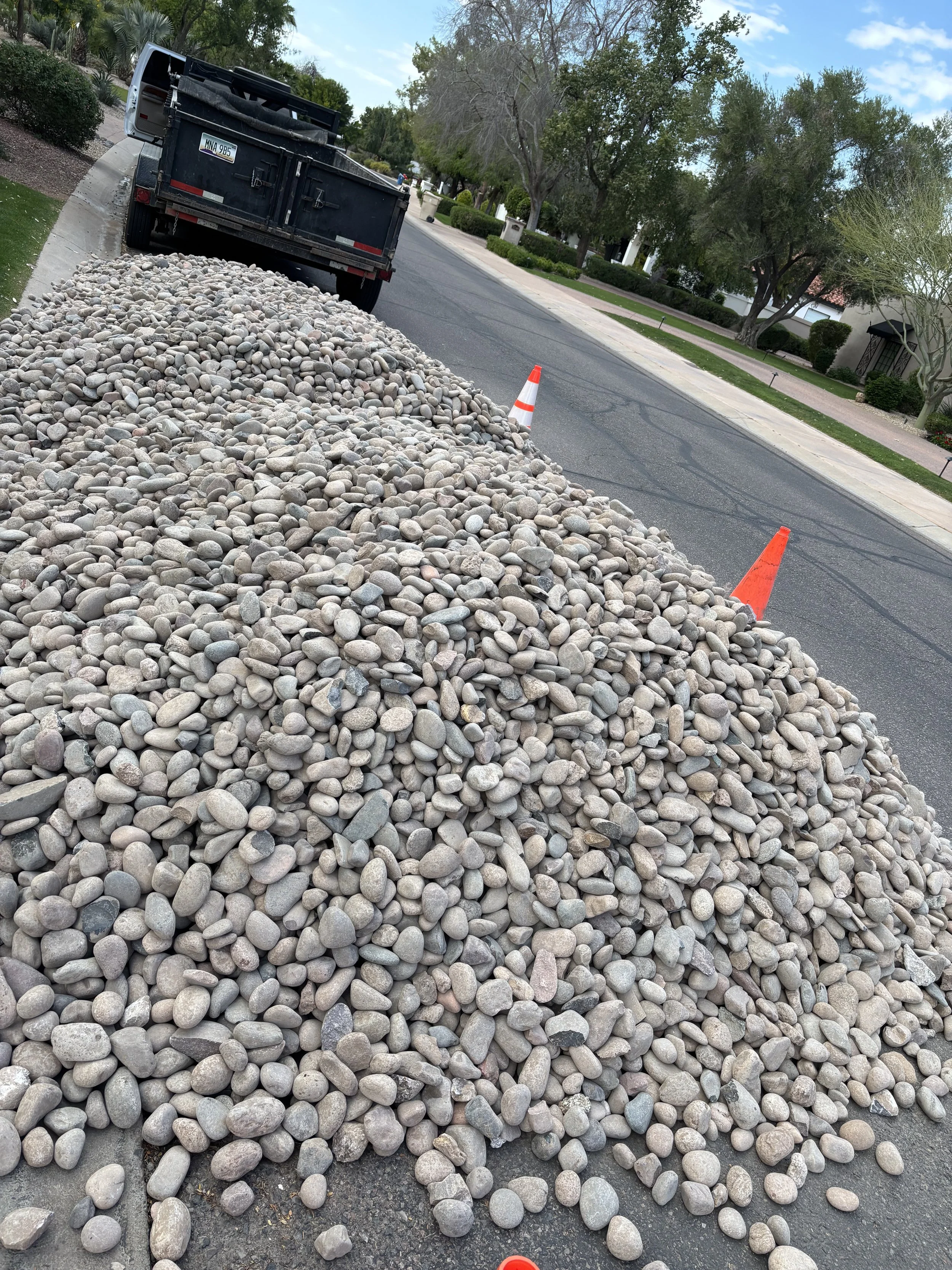 Pile of gravel on a sidewalk with traffic cones and a truck during a yard debris removal in Peoria