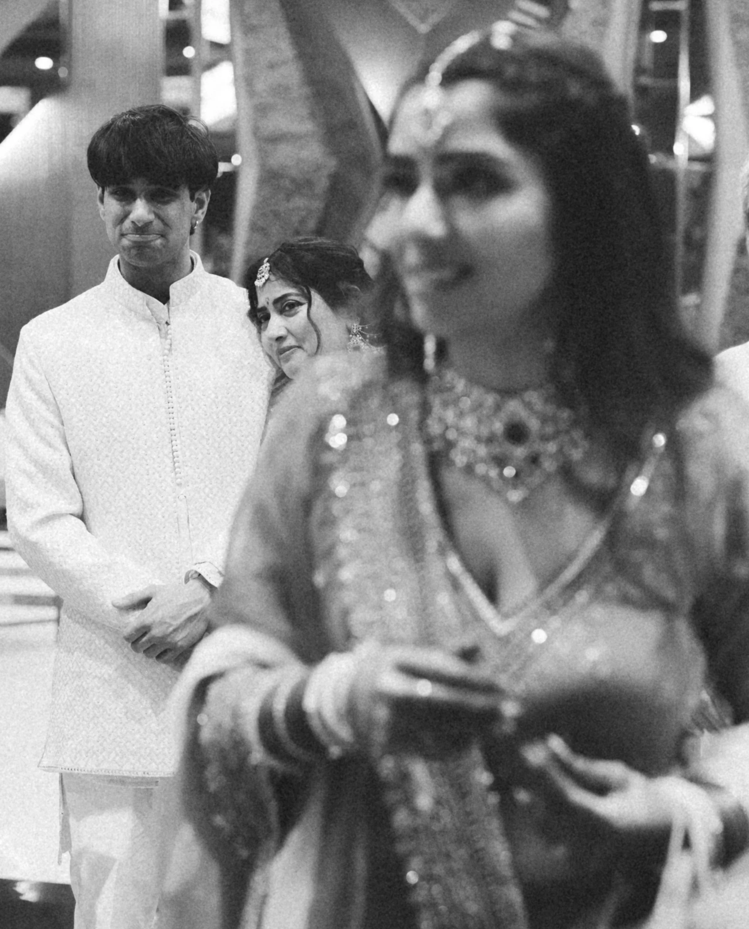 Three individuals dressed in traditional Indian attire at a celebration or event.