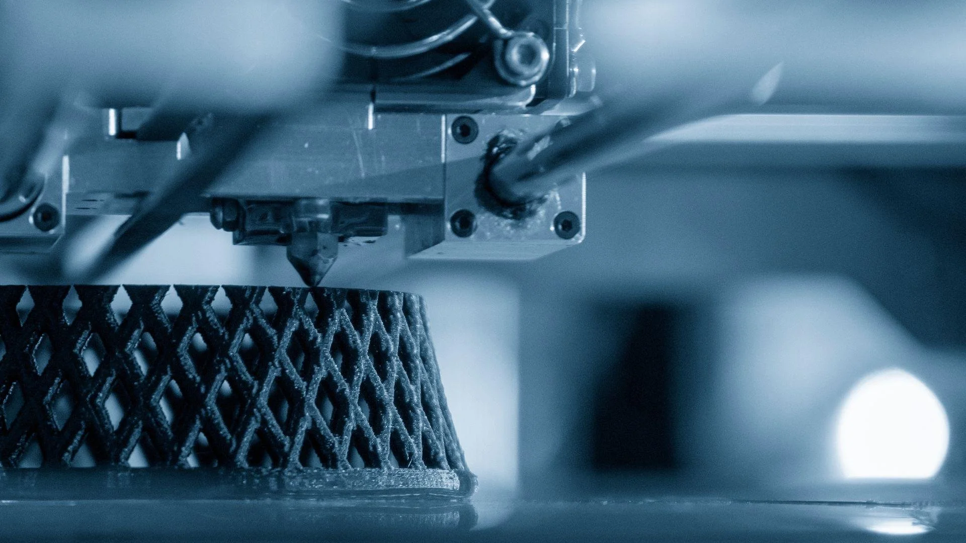 Close-up of a 3D printer creating a lattice structure with a printing nozzle.