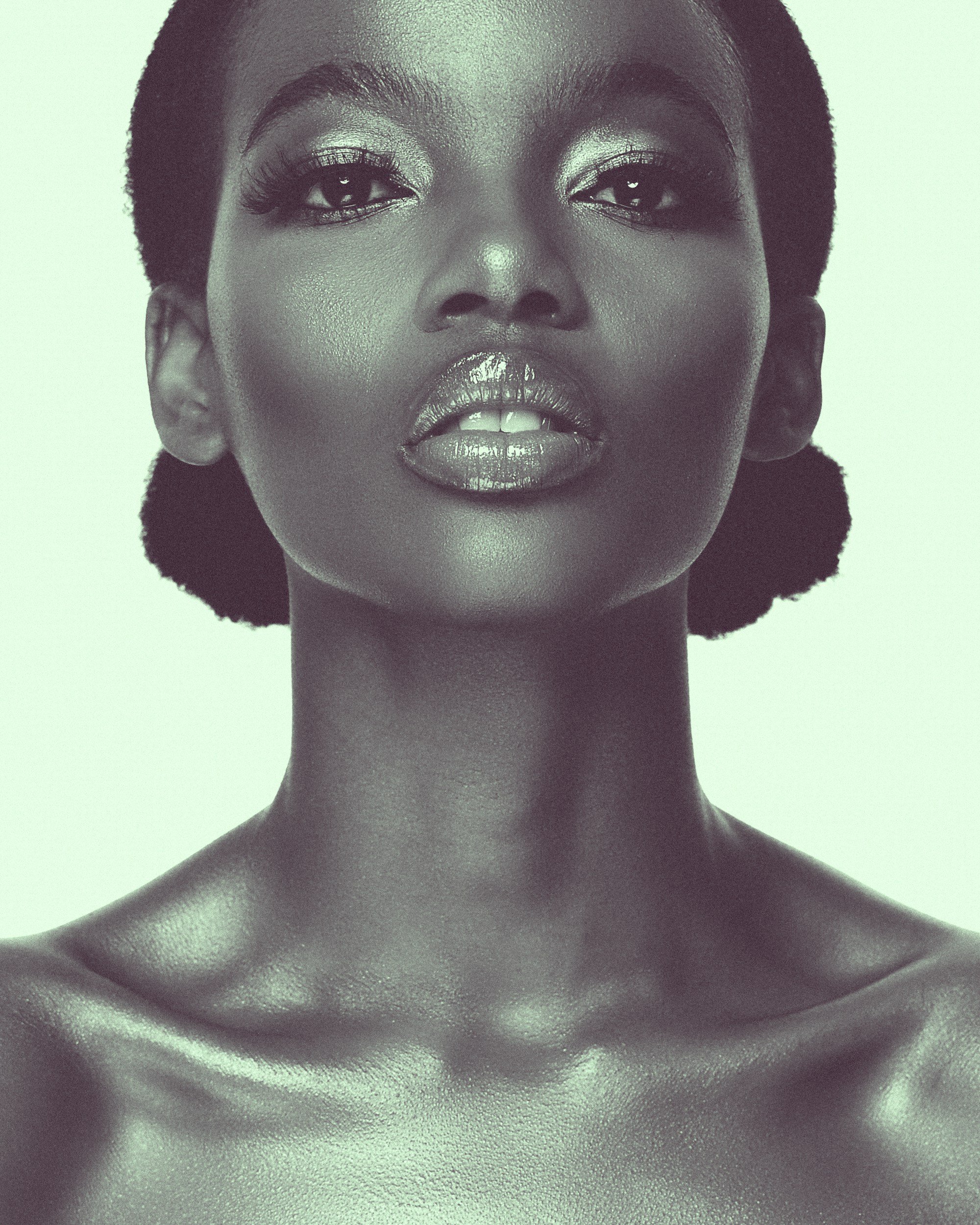A close-up black-and-white photo of a confident woman with short natural hair, striking makeup, and full lips.
