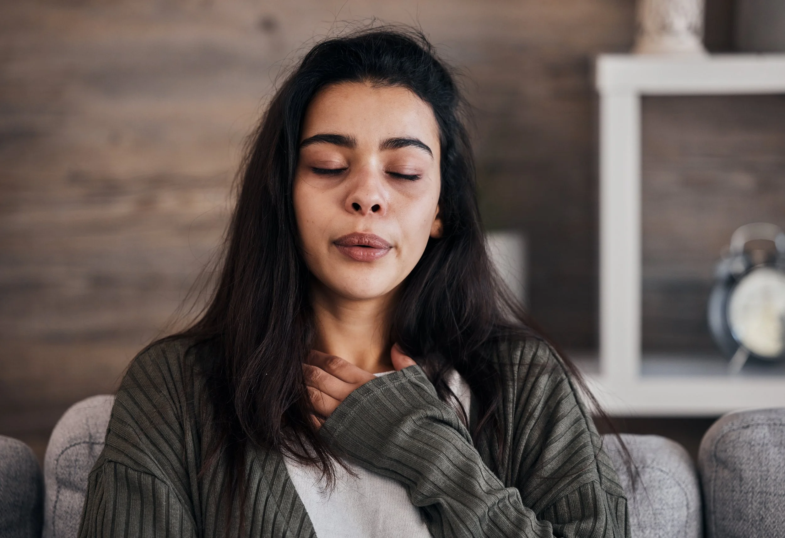 Woman with long brown hair breathing with her hand to her chest