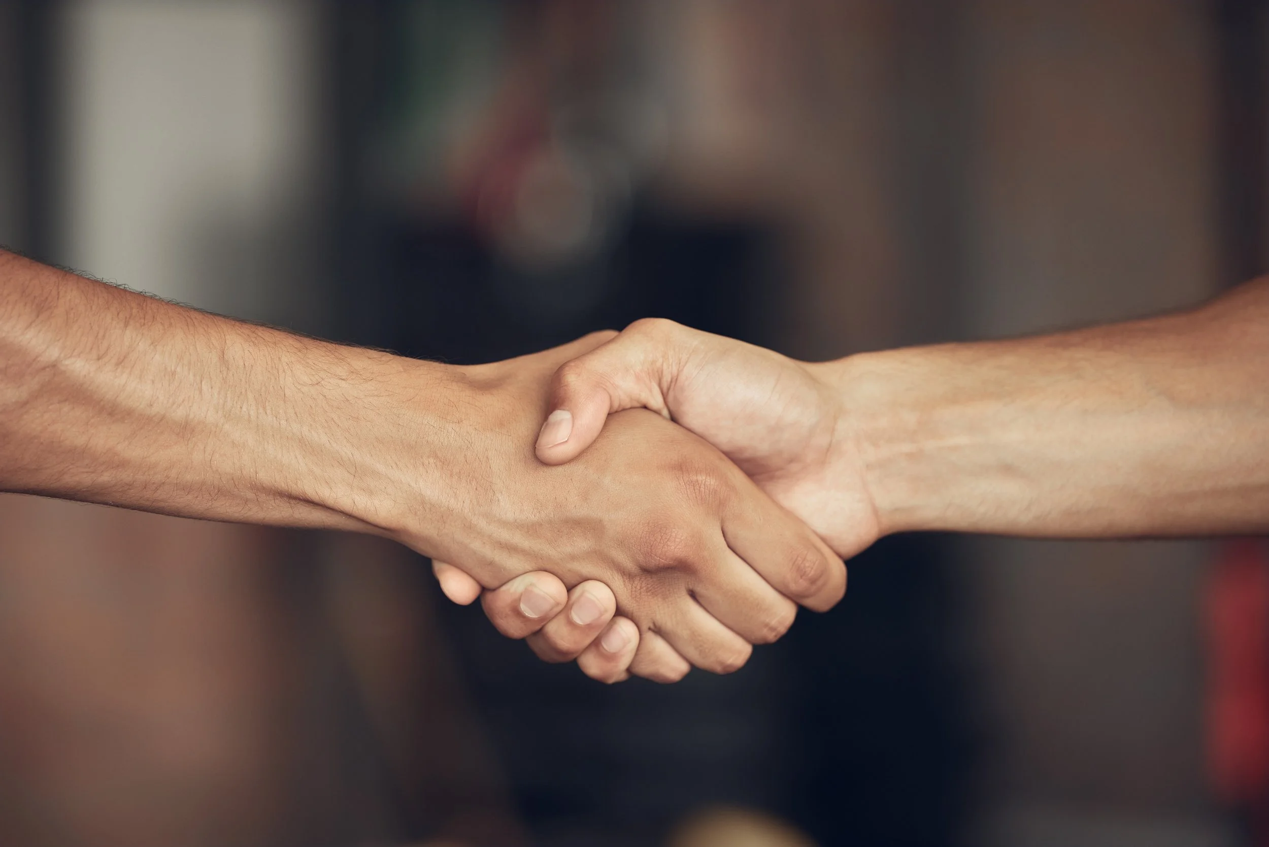 Close-up of two people shaking hands, symbolizing agreement or partnership.