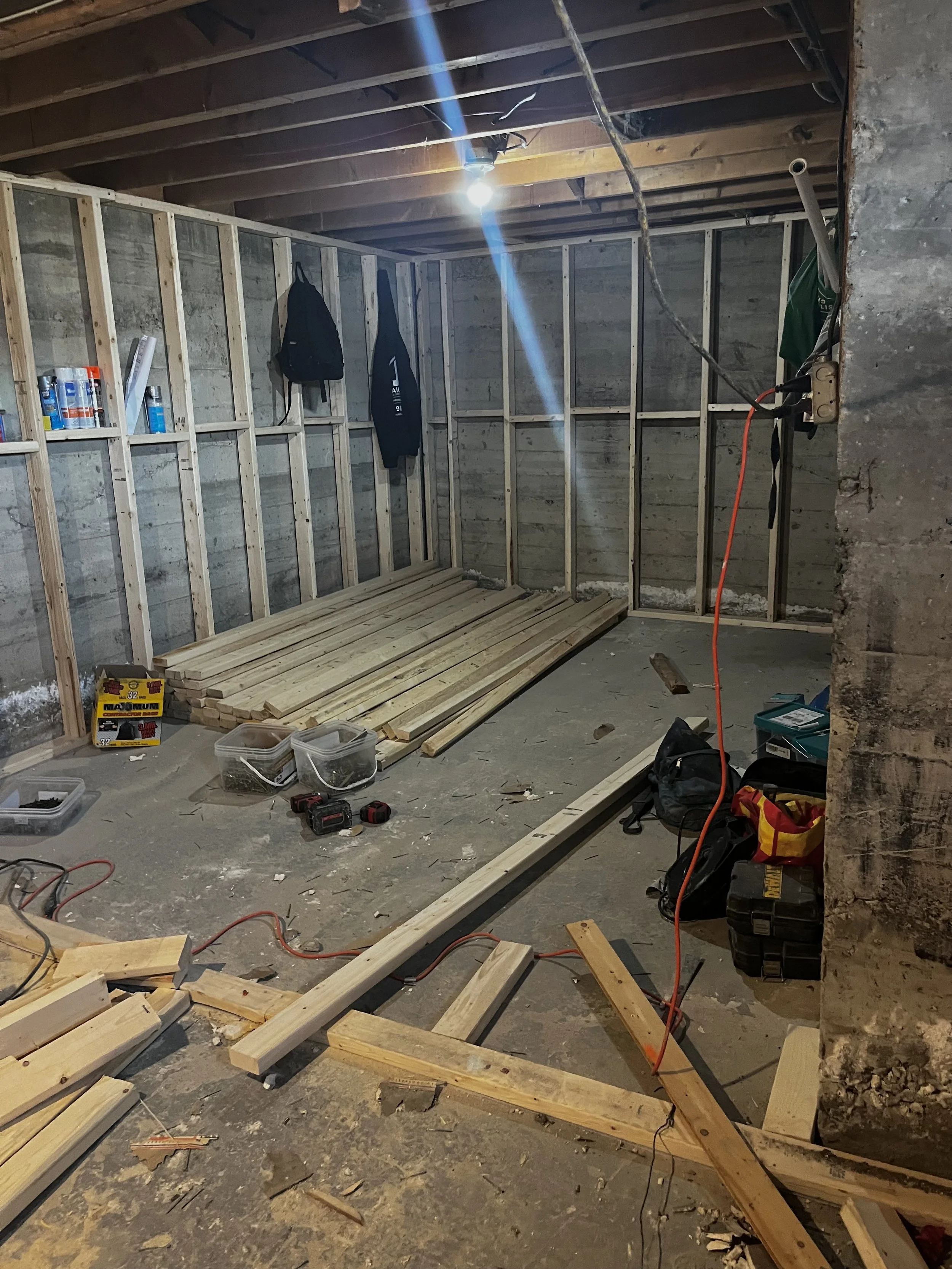 Room under construction with wooden framing, scattered tools, and building materials.
