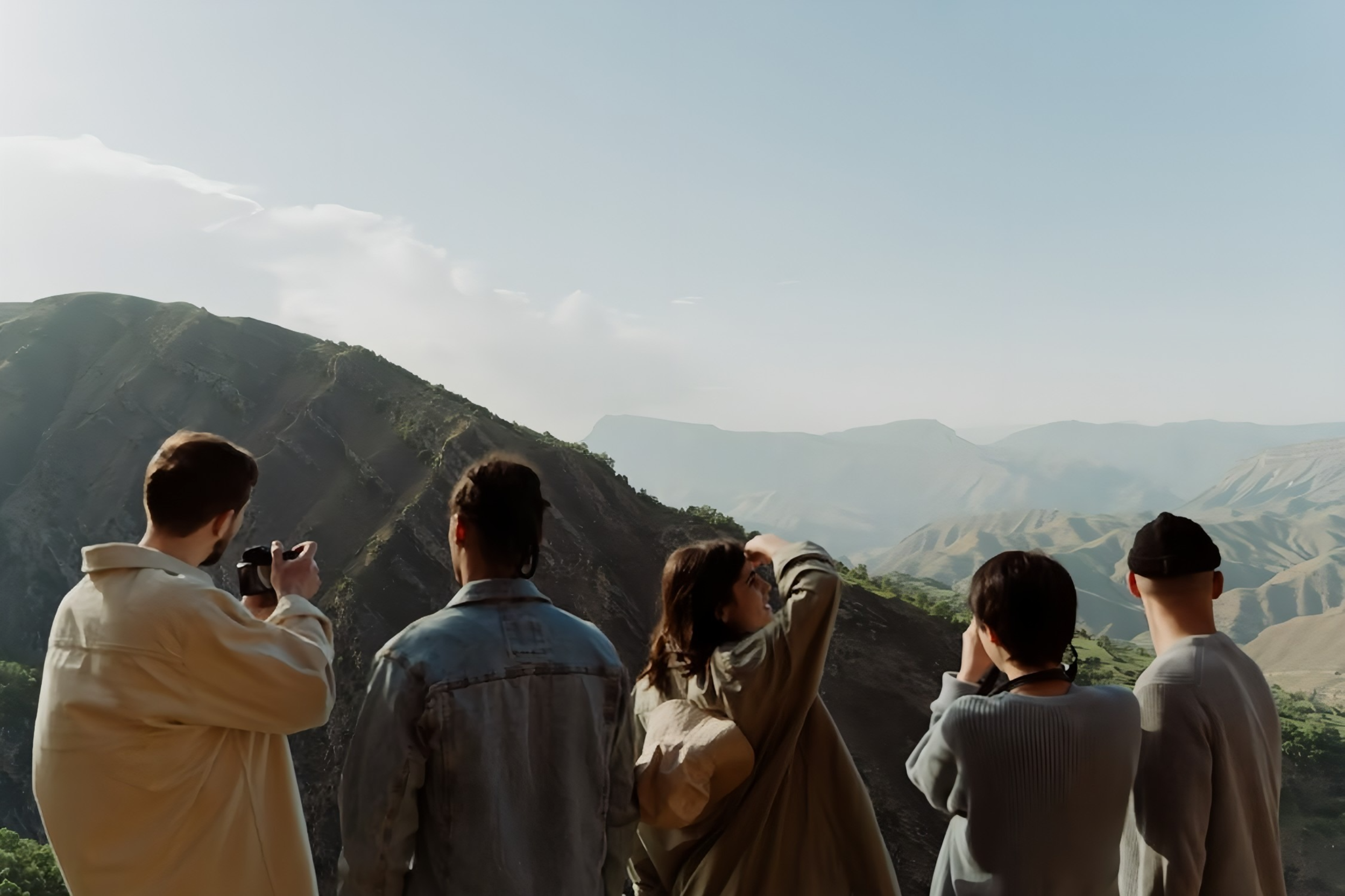 Groupe de personnes regardant un paysage de montagnes avec un ciel clair.