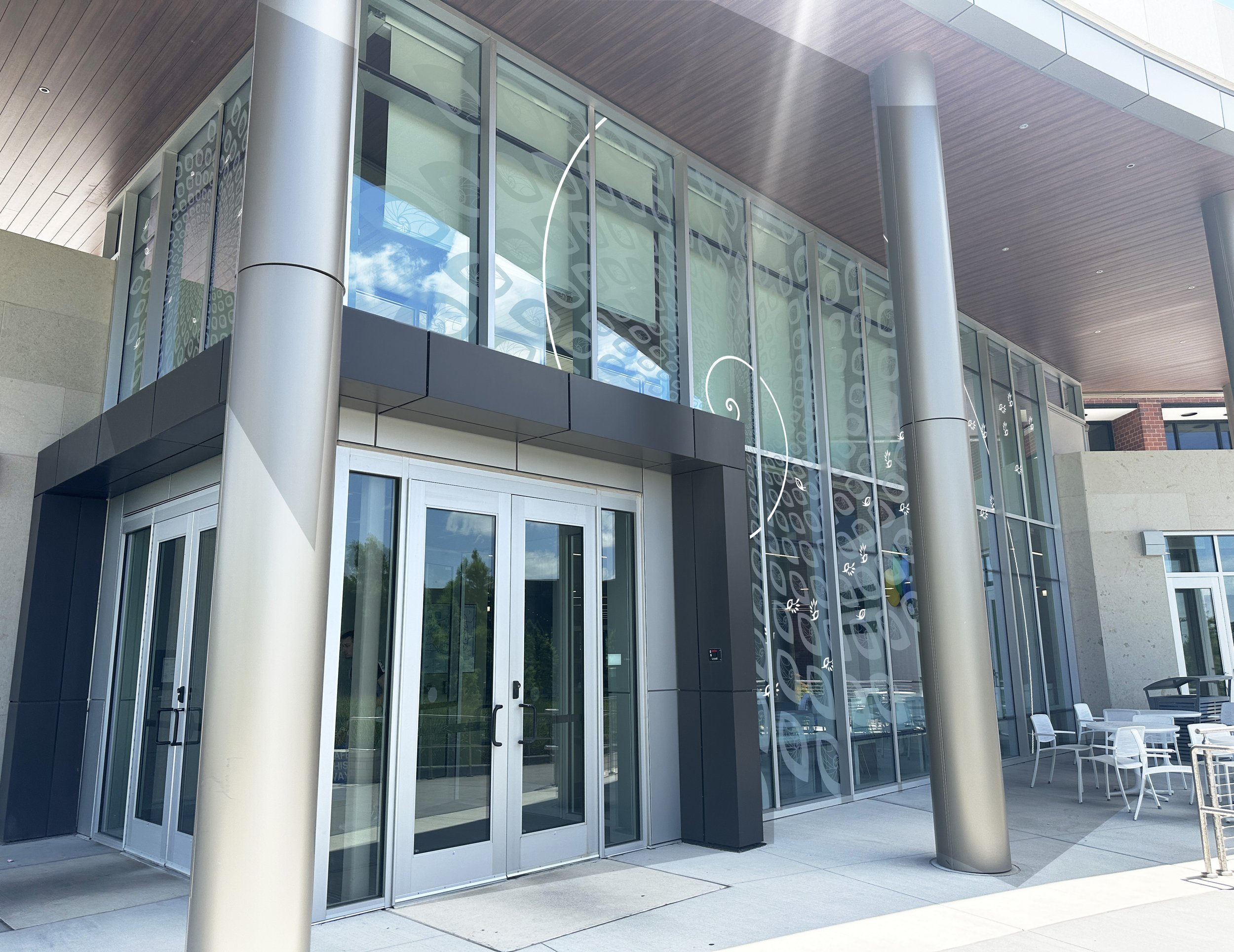 A photoshopped image of the student center with the vinyl applied how it would appear at ground level as people would approach the doors.