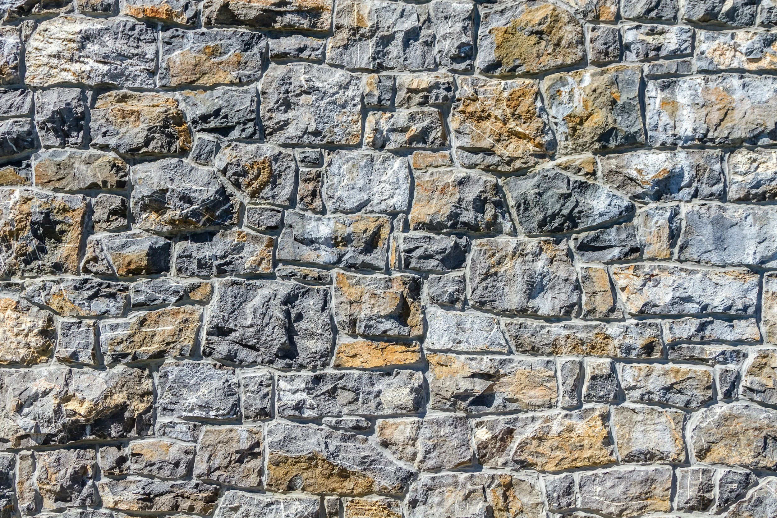 Close-up of a textured gray stone wall with irregularly shaped stones and mortar.