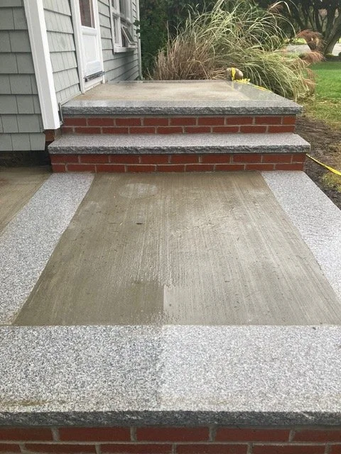New concrete porch with granite border and brick steps leading up to the house.