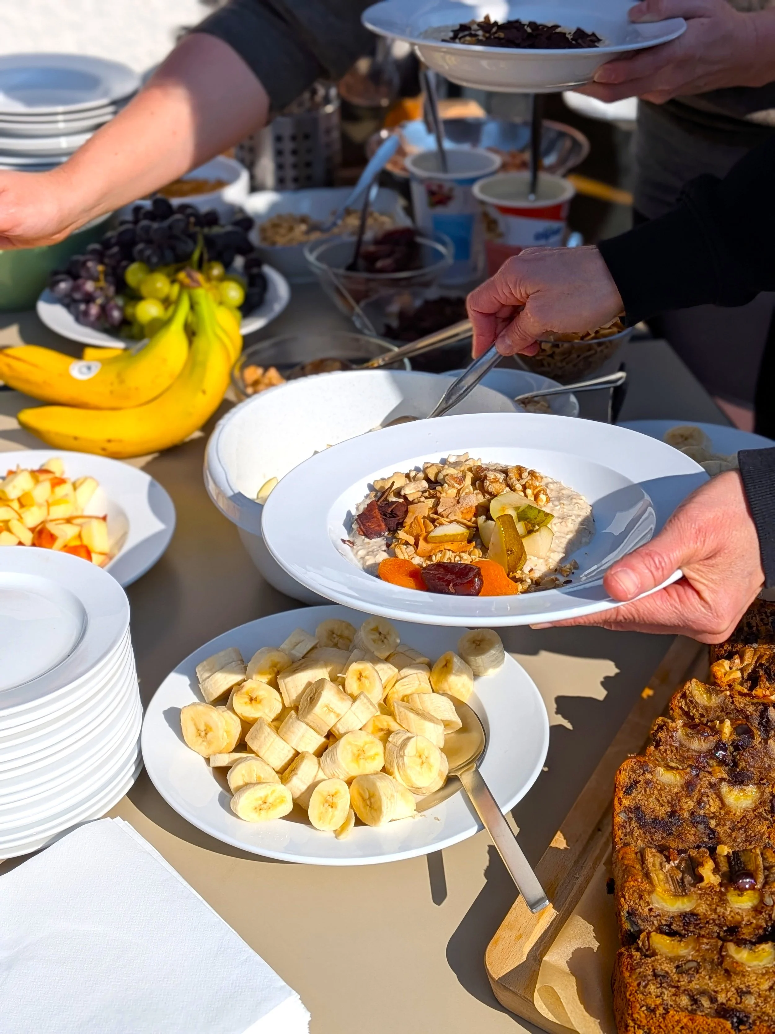 Bunte Früchte, Joghurt mit Müsli, Bananen, gerösteter Kuchen auf einem Buffet bei einer outdoor Veranstaltung.