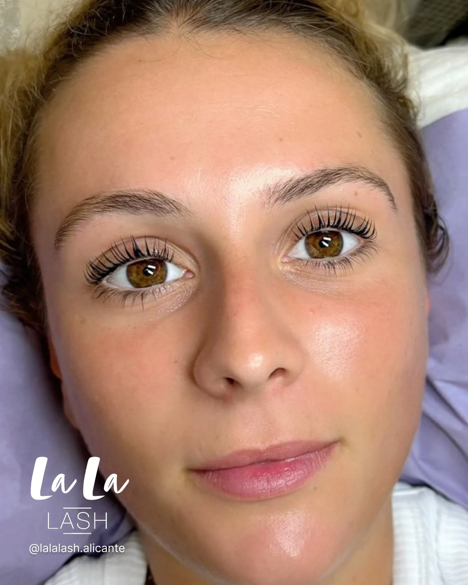  rostro de una mujer con piel clara y ojos marrones, en un entorno de spa o clínica de belleza, con un moño en el cabello y una expresión relajada