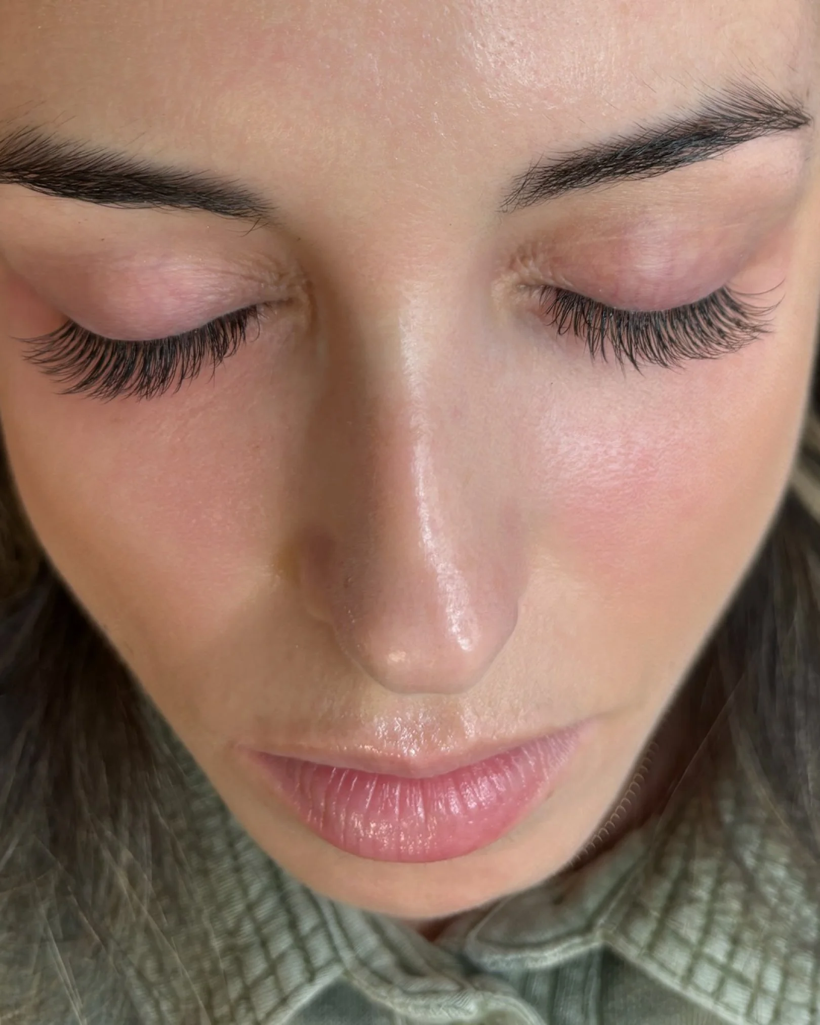 Primer plano de una mujer con los ojos cerrados mostrando sus pestañas largas y cejas oscuras.