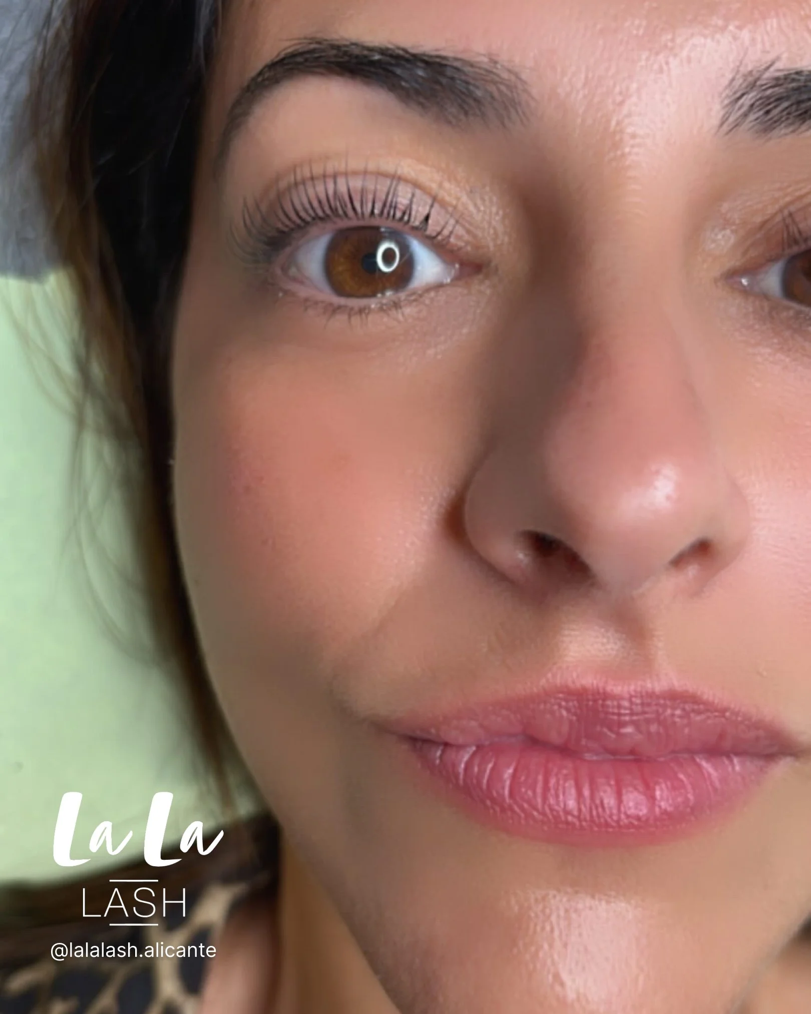 Cerca de un ojo de una mujer, con pestañas largas y cejas bien definidas, piel clara y labios rosados. Texto en la esquina inferior izquierda que dice 'La La LASH' y el manejo de redes sociales '@lalalash.alicante'.