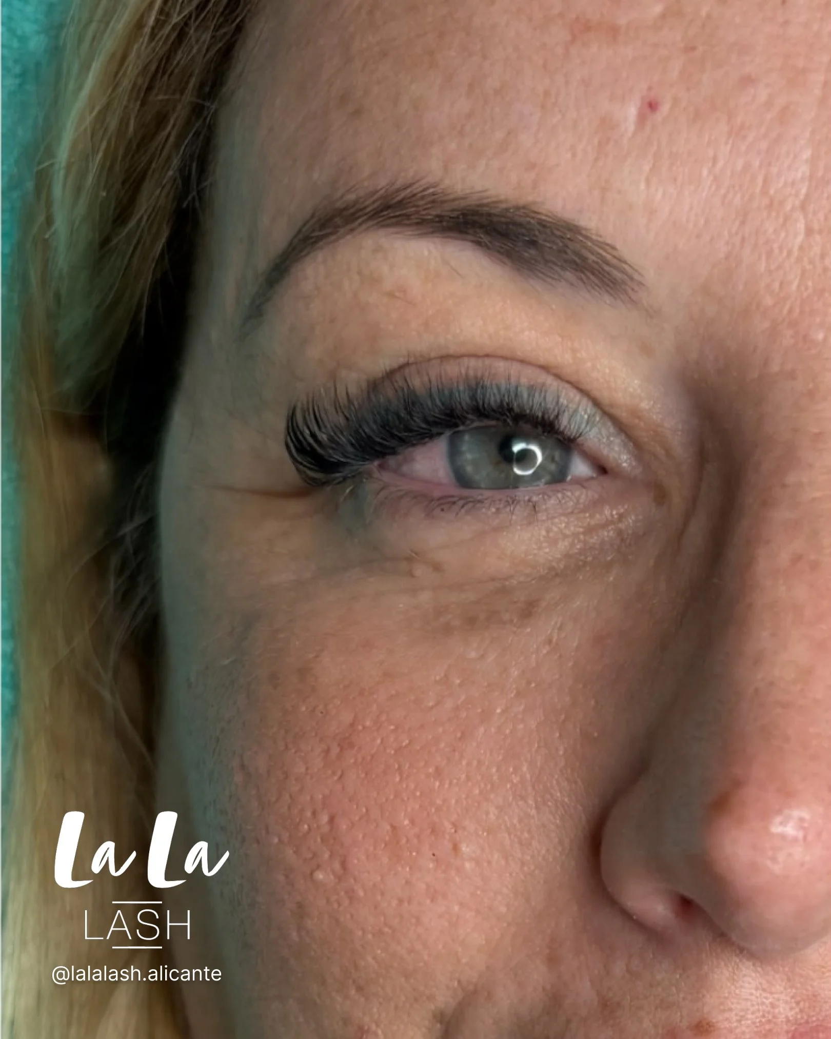 Cerca de un ojo humano con pestañas postizas, ceja arreglada y piel con textura y detalles visibles.