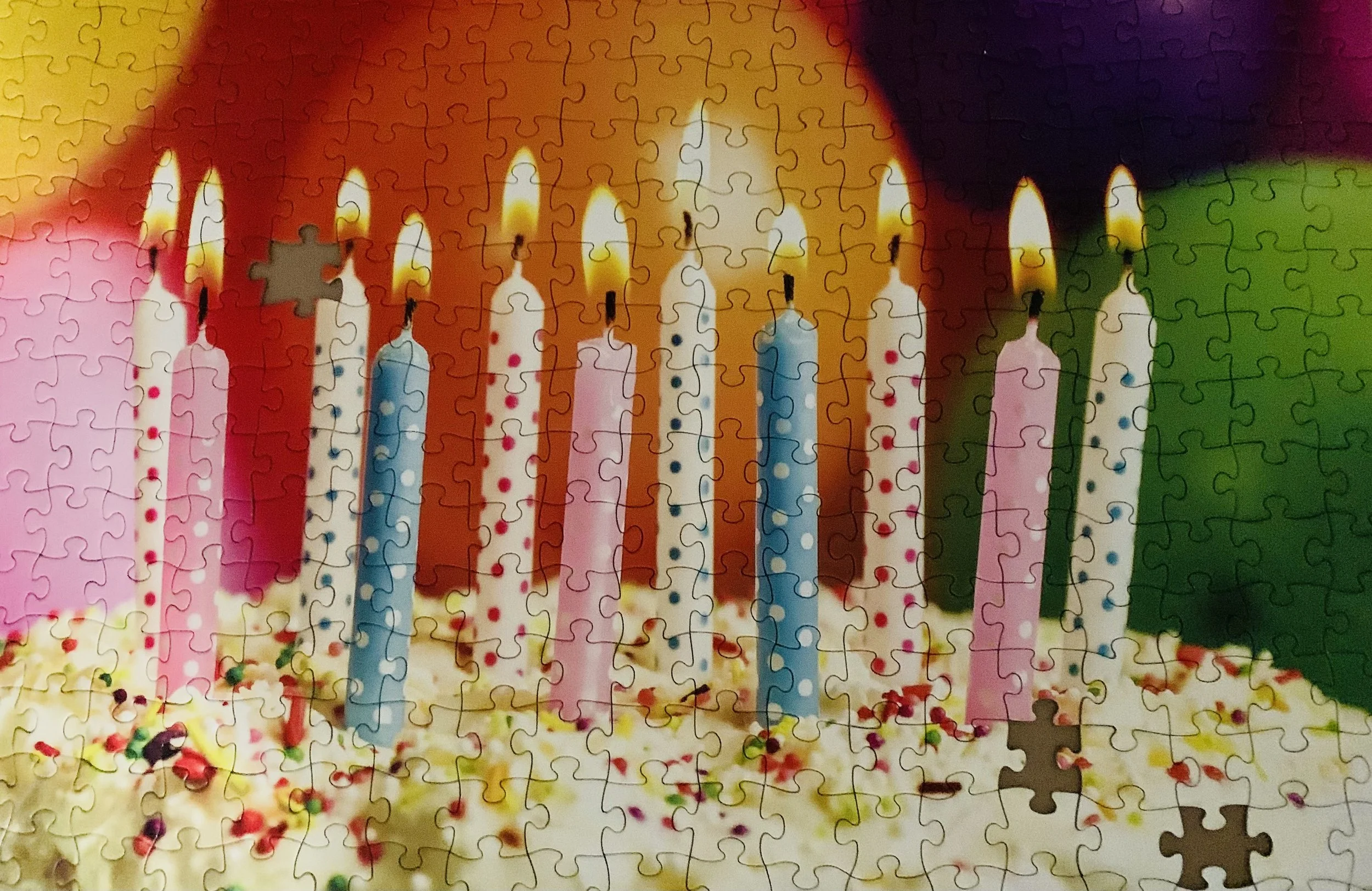 A birthday cake puzzle with a few pieces missing.