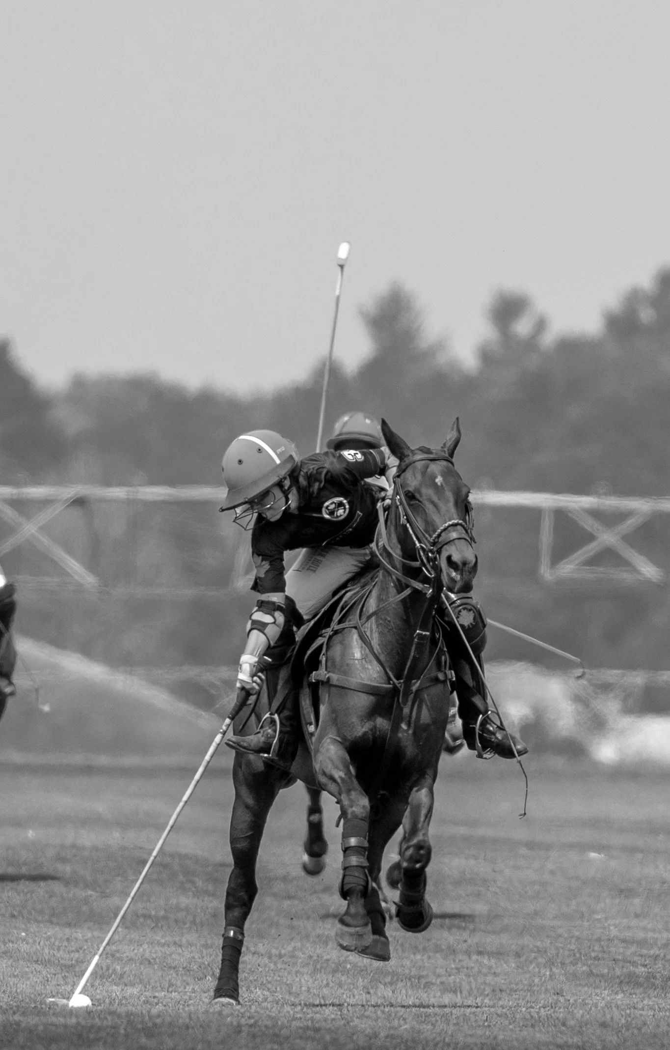 A polo player on horseback striking the ball with a mallet during a polo match.