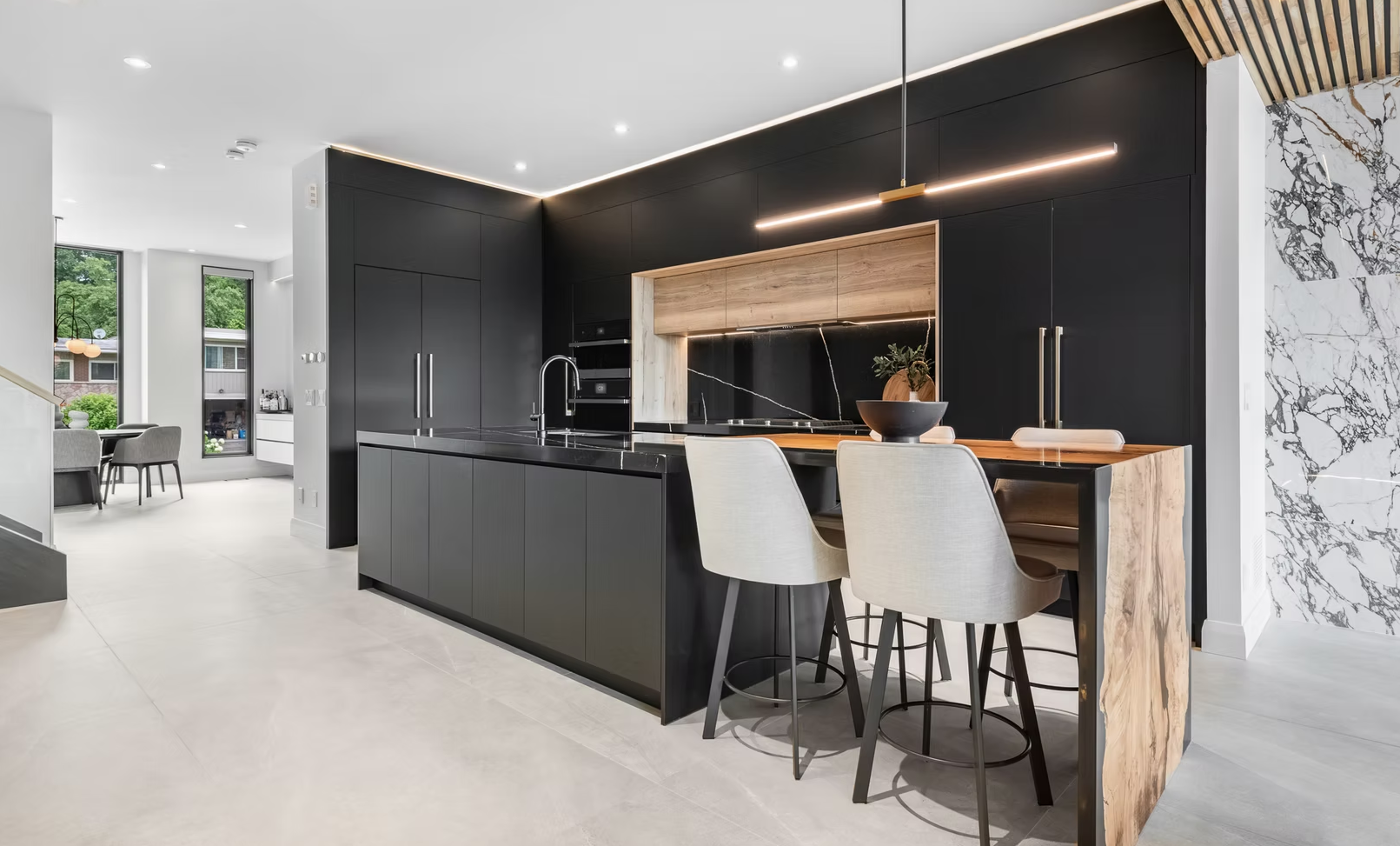 Modern kitchen with black cabinets, wooden accents, and an island with bar stools