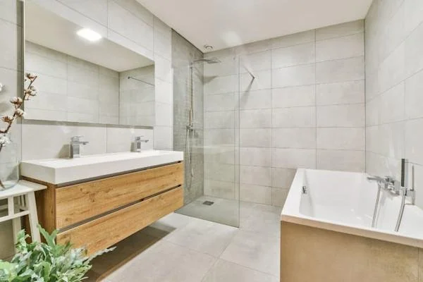 Modern bathroom with dual sinks, large mirror, glass-enclosed shower, and a bathtub.