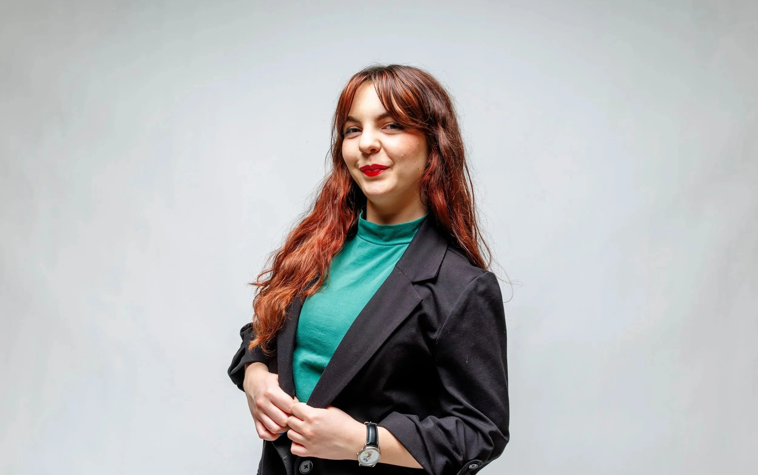 Chelsea is smiling at the camera wearing a green shirt and black blazer.