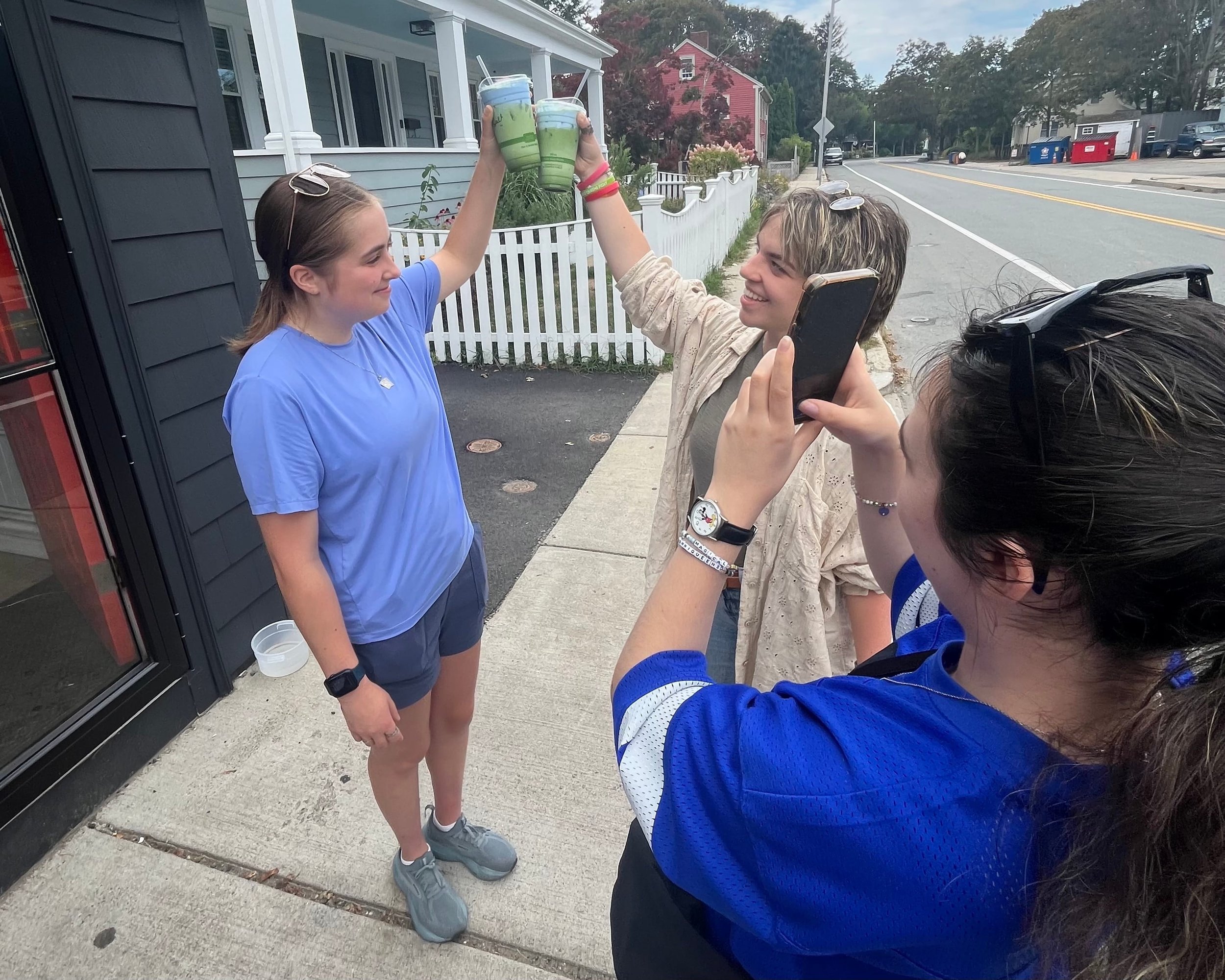 Chelsea filming two people holding Endicott themed drinks while filming a video.