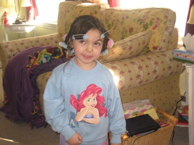 4-year-old Chelsea poses while wearing hair rollers and a Princess Ariel sweatshirt.