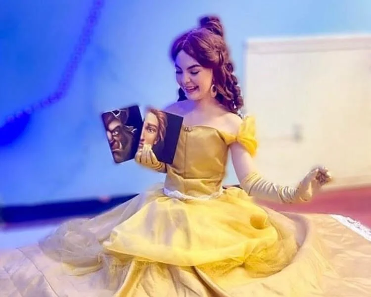 Chelsea, dressed as a princess, sits on the floor holding books. 
