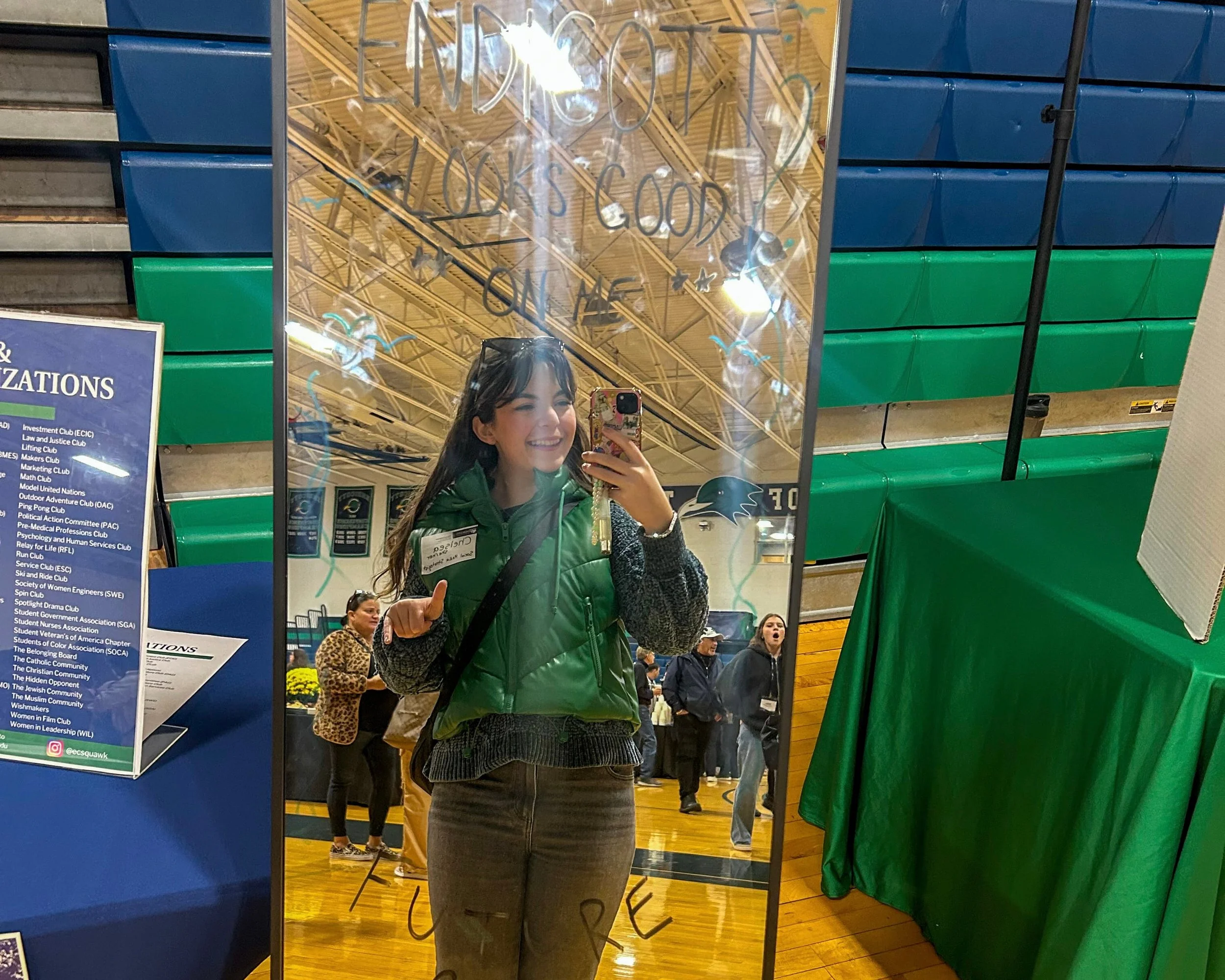 Chelsea is taking a photo in an Endicott College themed mirror.