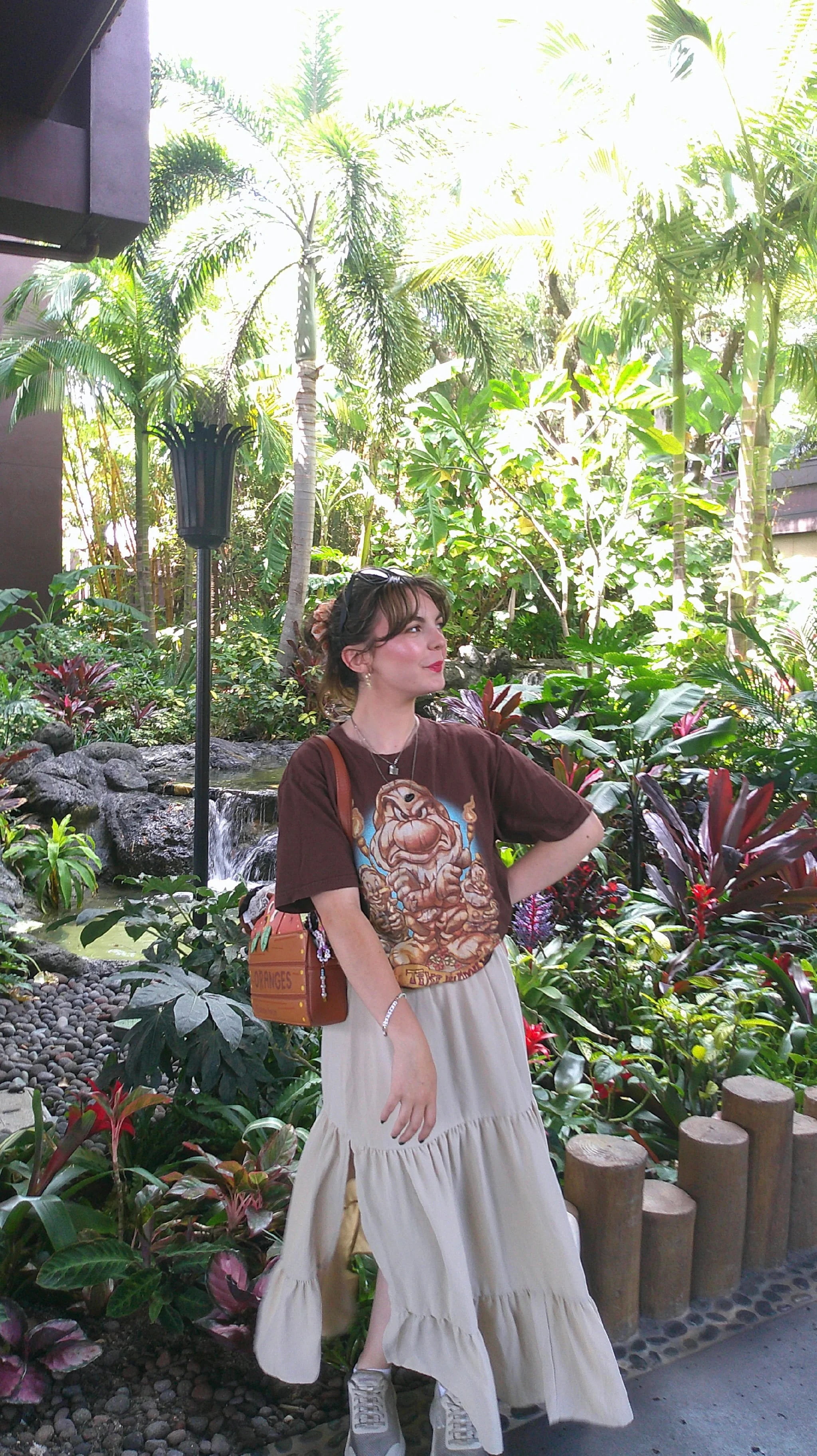 Chelsea poses in front of a lush garden at Disney's Polynesian Village Resort.