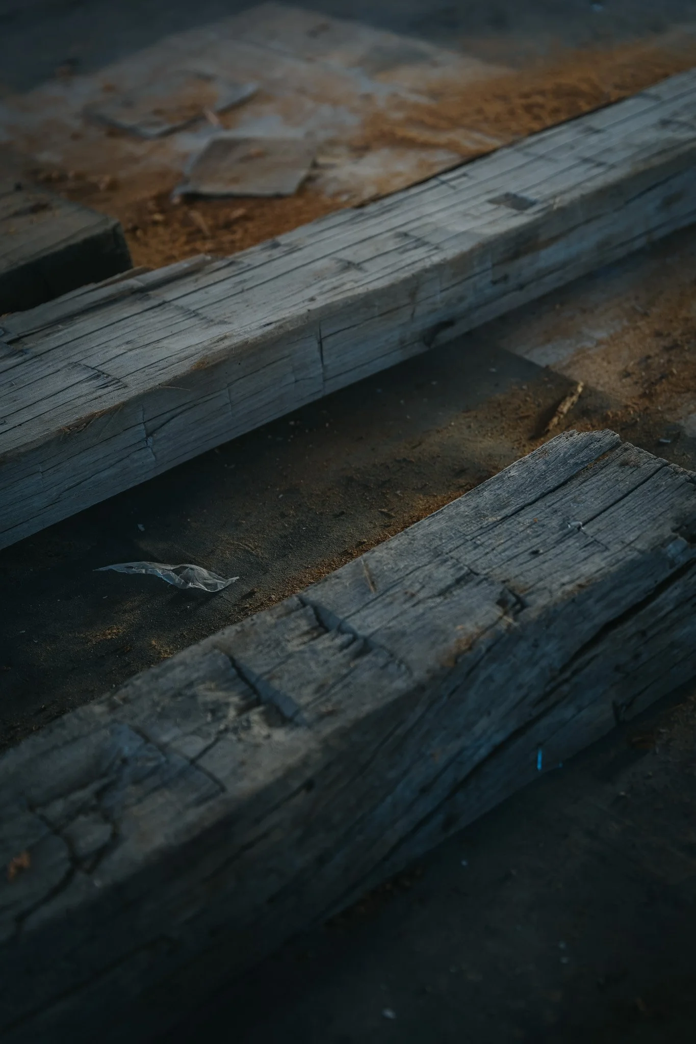 Close-up of weathered wooden planks on a dark ground with some scattered debris and dirt.