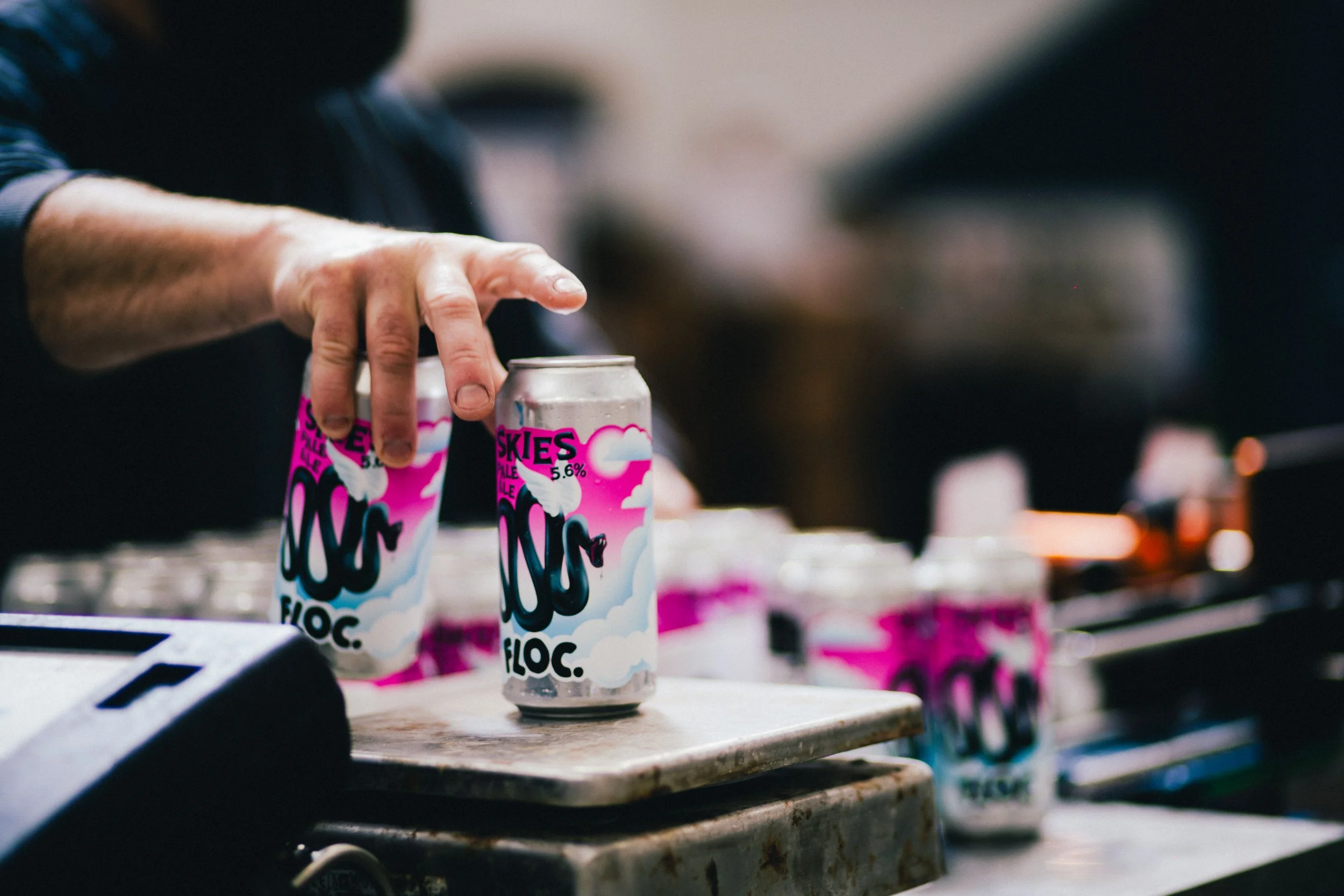 Person arranging cans of Skies Seltzer on a table in a commercial setting.