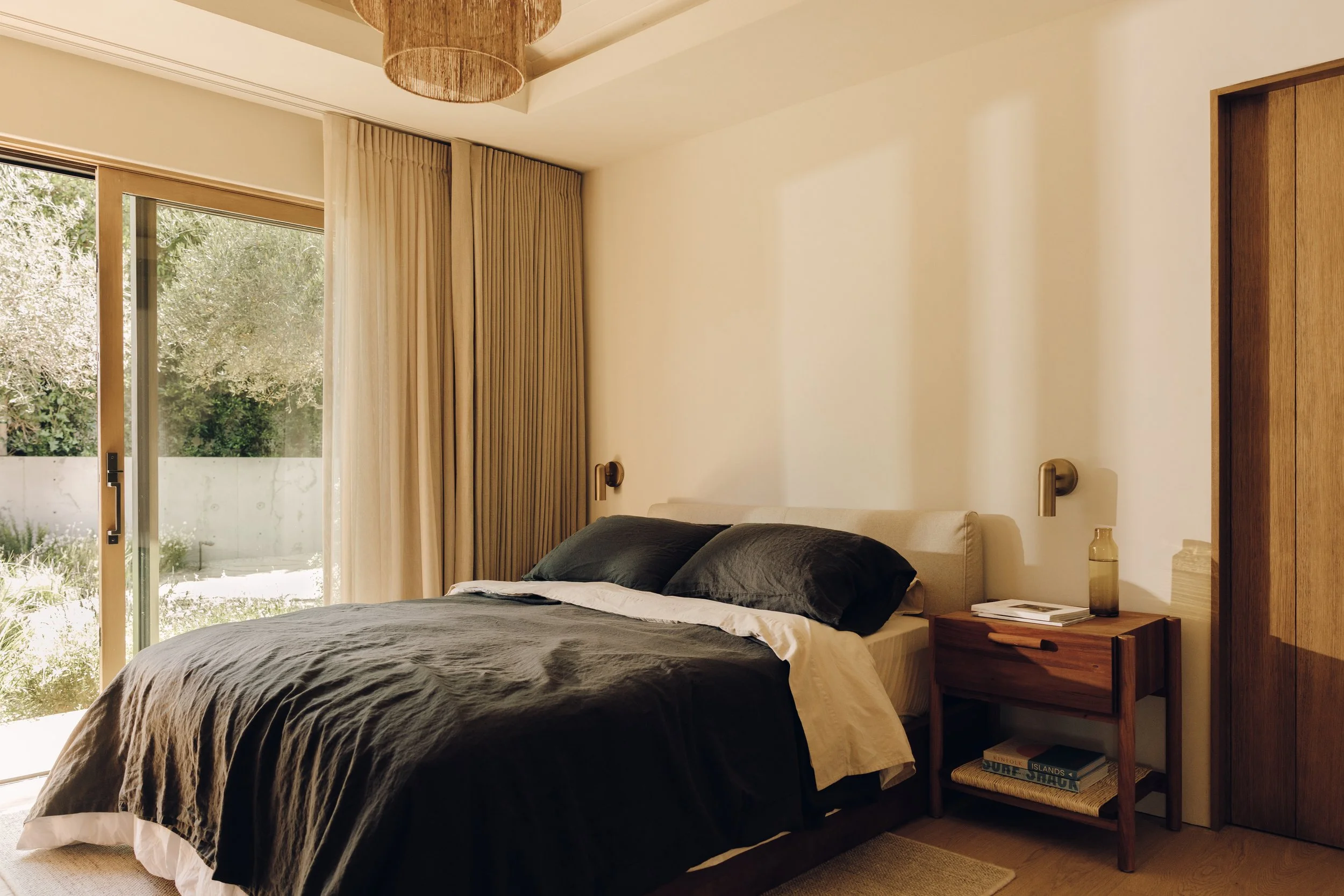 Bedroom with dark bedding and garden-facing windows