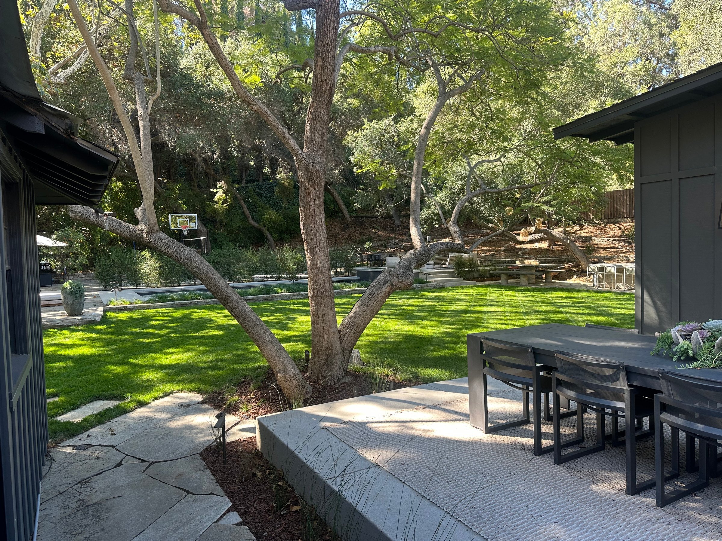 Dining terrace with views toward the pool and mature oak trees. | PL-3803