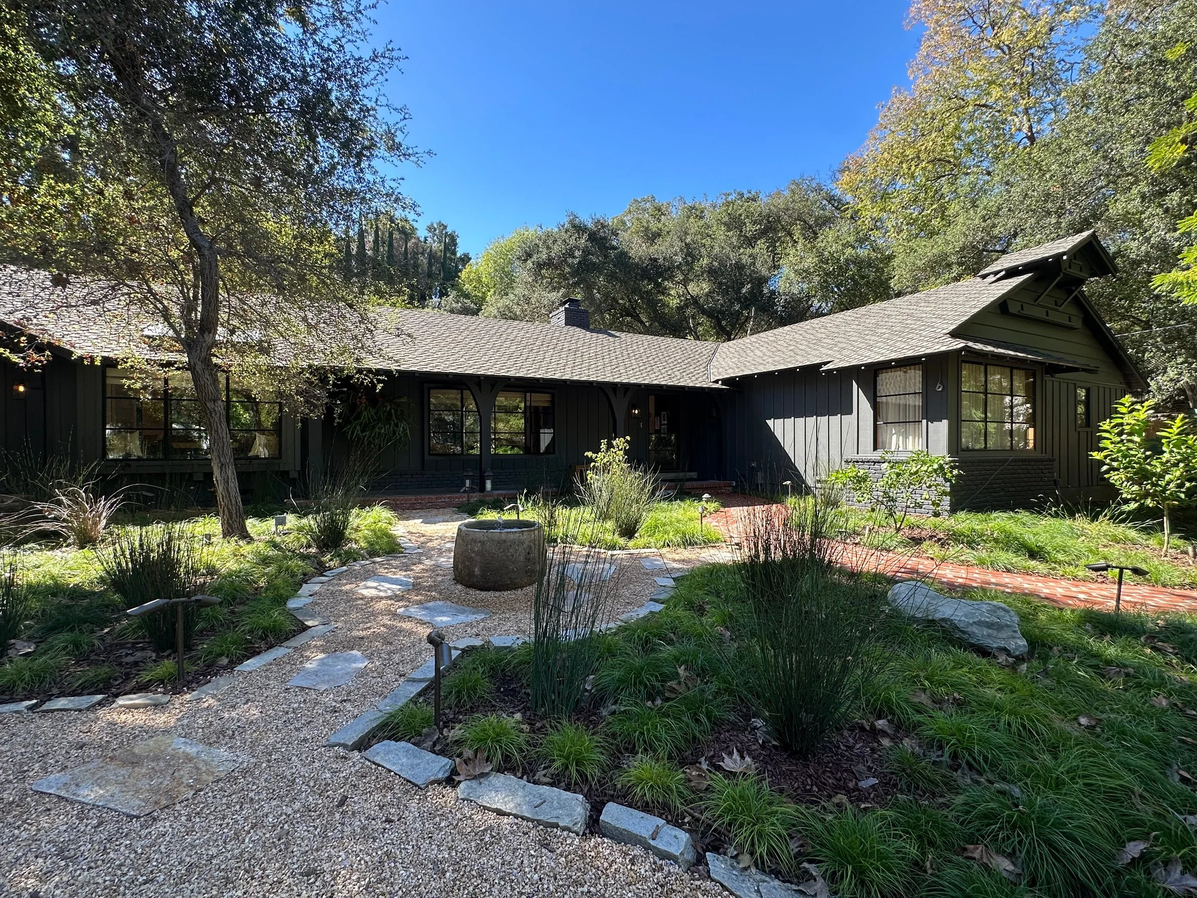 Front elevation with dark board and batten siding, birdhouse gable and landscaped garden. | PL-3803