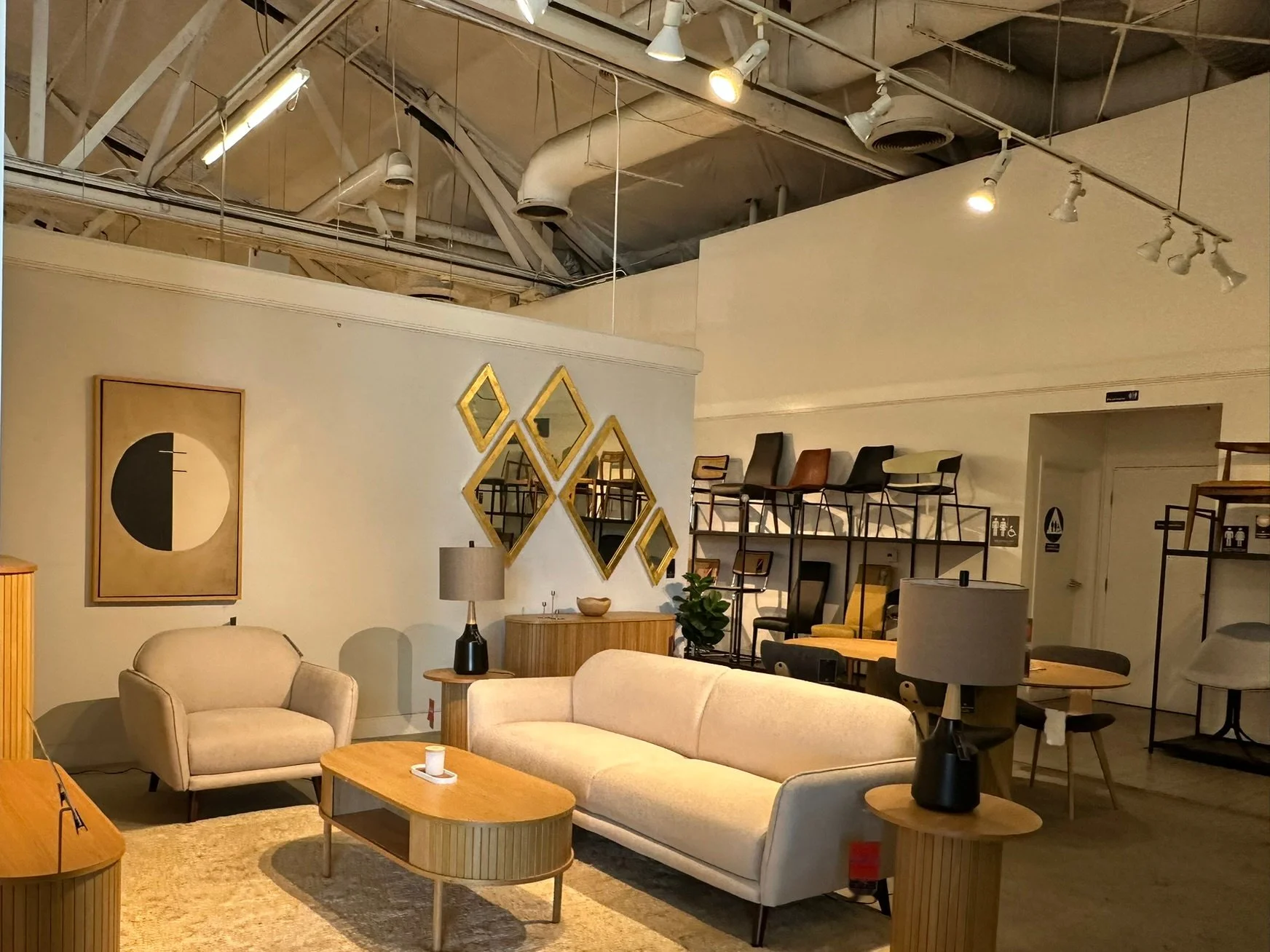 Warm showroom interior with exposed ceiling structure. Earlier furnished condition; pictured furniture is not included.