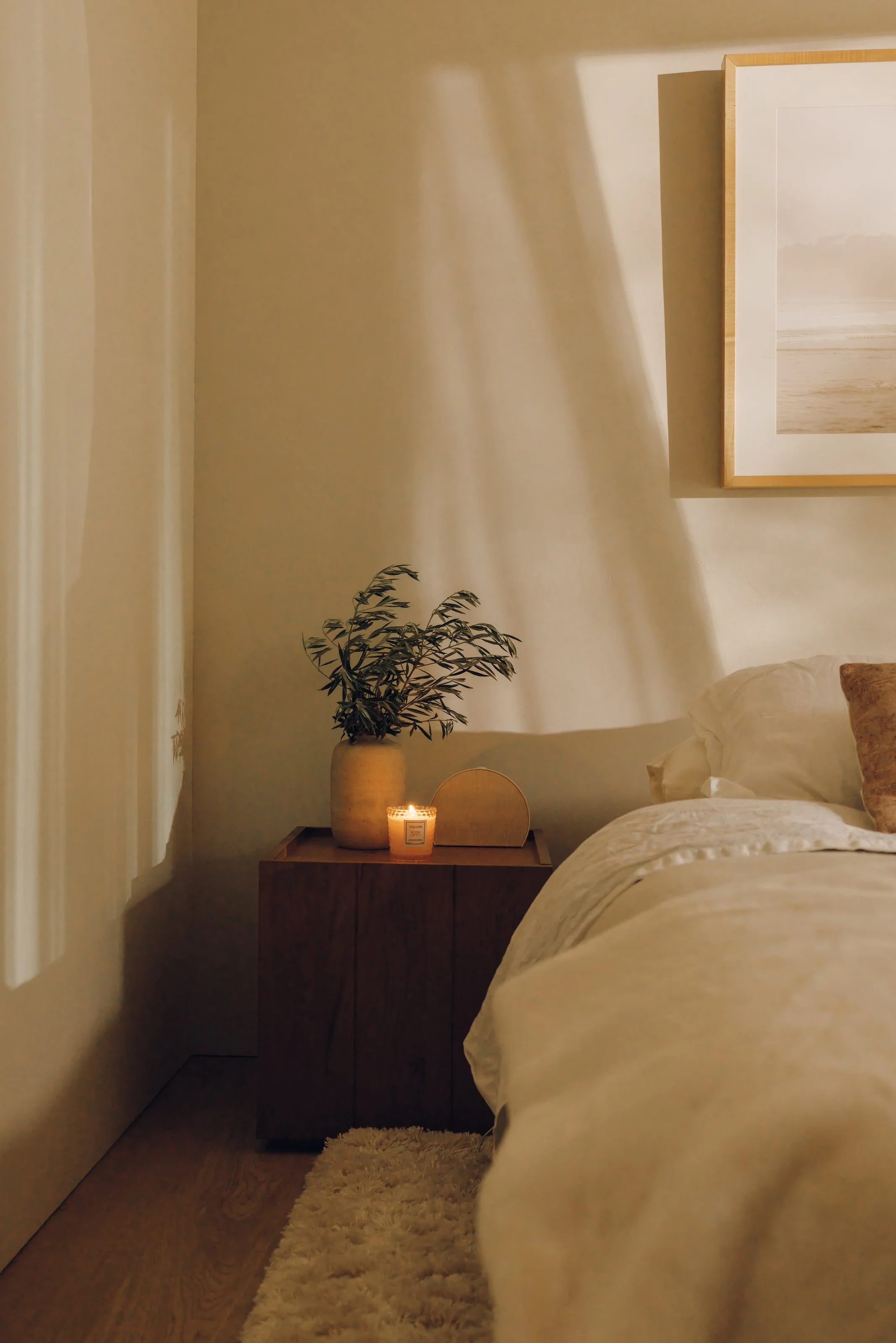 Bedroom with soft neutral bedding and bedside light