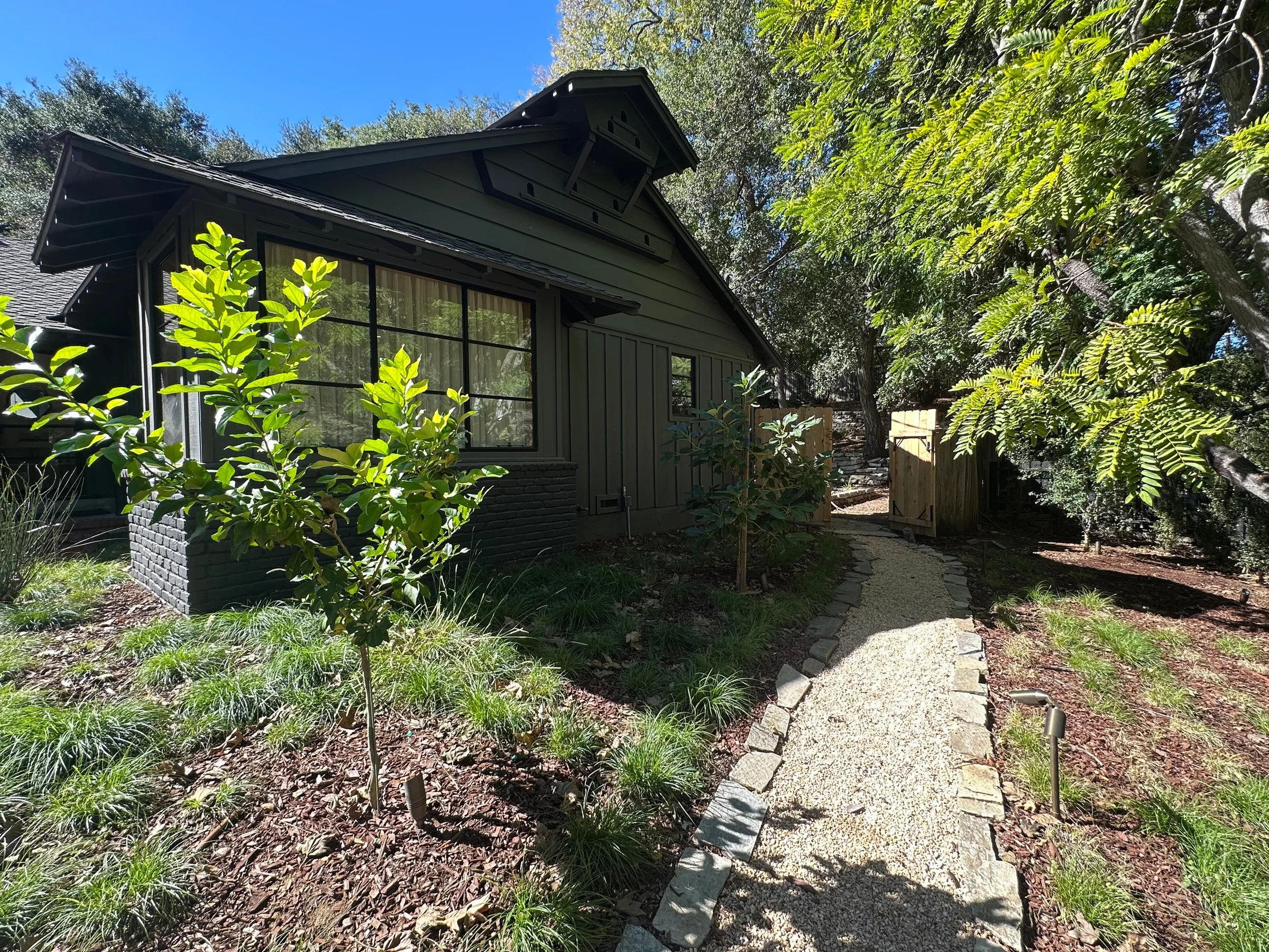 Birdhouse gable and planted garden path beside the house. | PL-3803