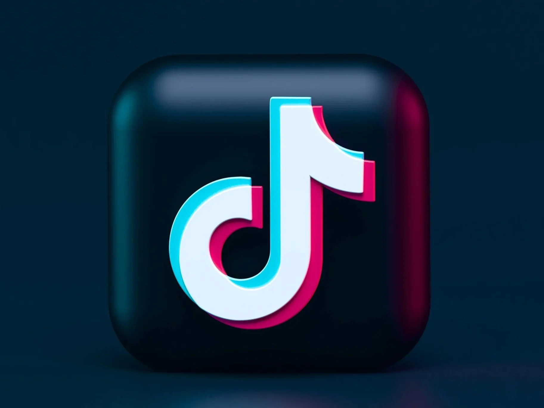 Close-up of the TikTok app logo, a musical note in white outlined with cyan and pink, on a dark background.