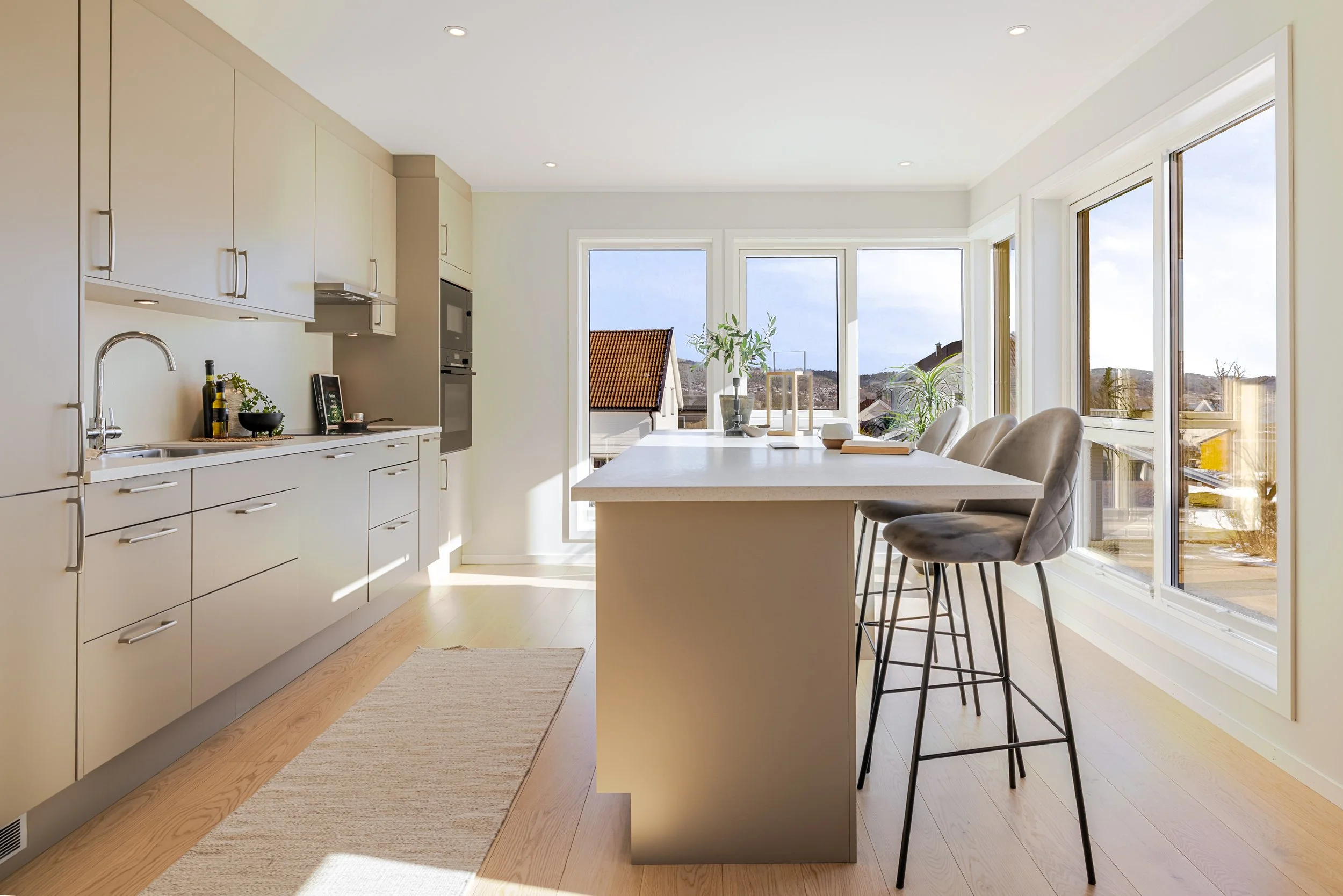 To personer som arbeider ved et bord med en åpen bærbar, en notisbok, en penn, og et glass vann, mens det er en vase med to hvite calla liljer og en liten dekorativ vase på bordet.