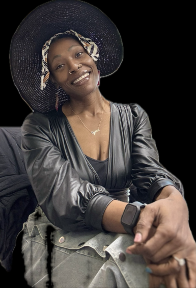 Woman wearing a large straw hat with a decorative bow, smiling, dressed in a black leather top, with a watch and necklace, sitting against a dark background.