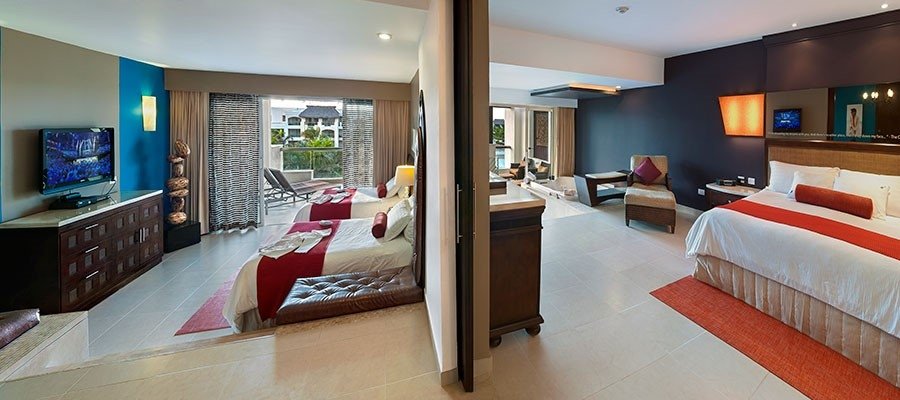 Split view of two hotel rooms, each with beds, chairs, and decor, separated by a wall and door