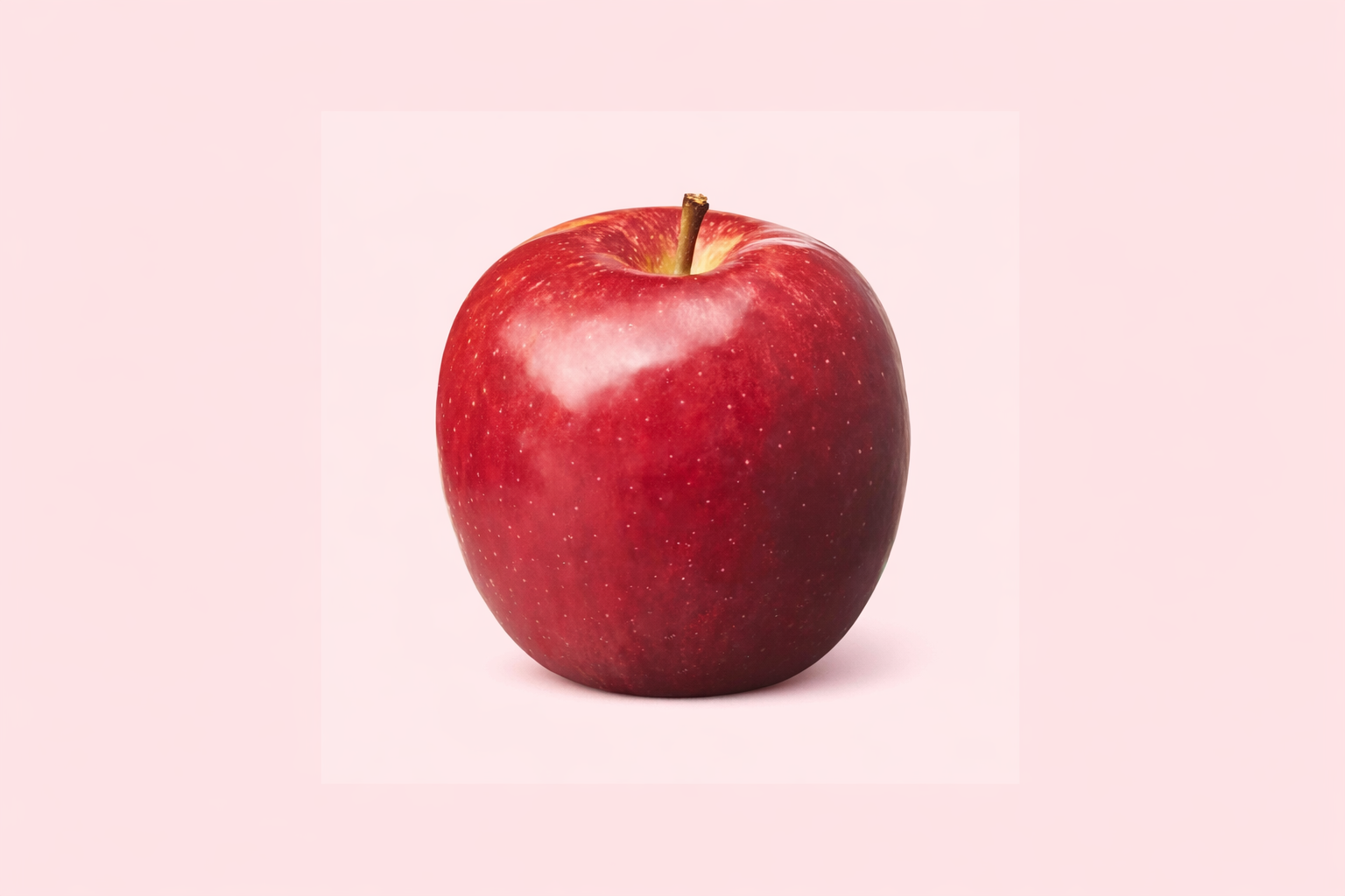 A red apple with a small brown stem on a light pink background.