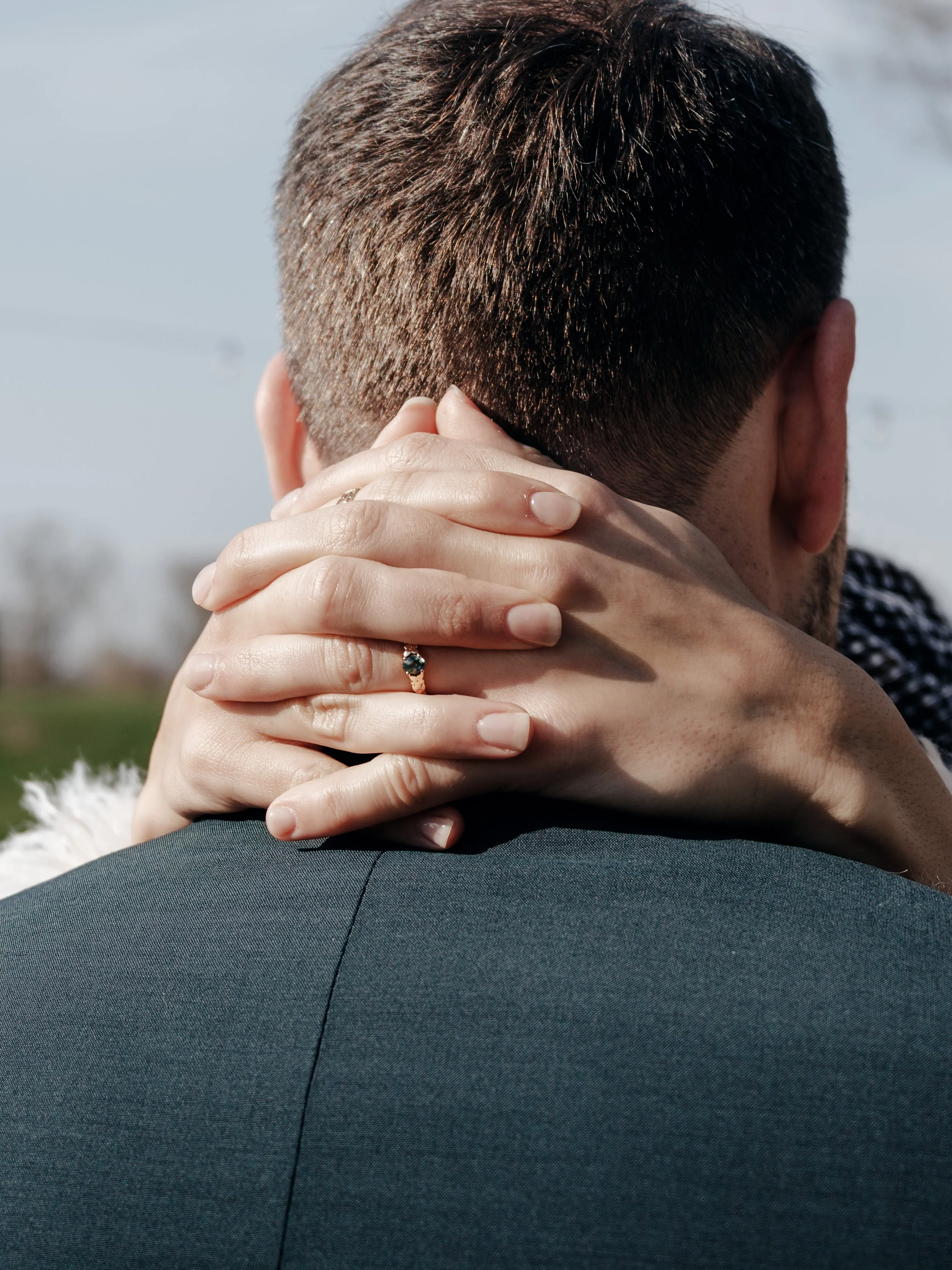 Nahaufnahme von einem Paar, das sich umarmt, mit einem Fokus auf die Hände und den Rücken eines Mannes.