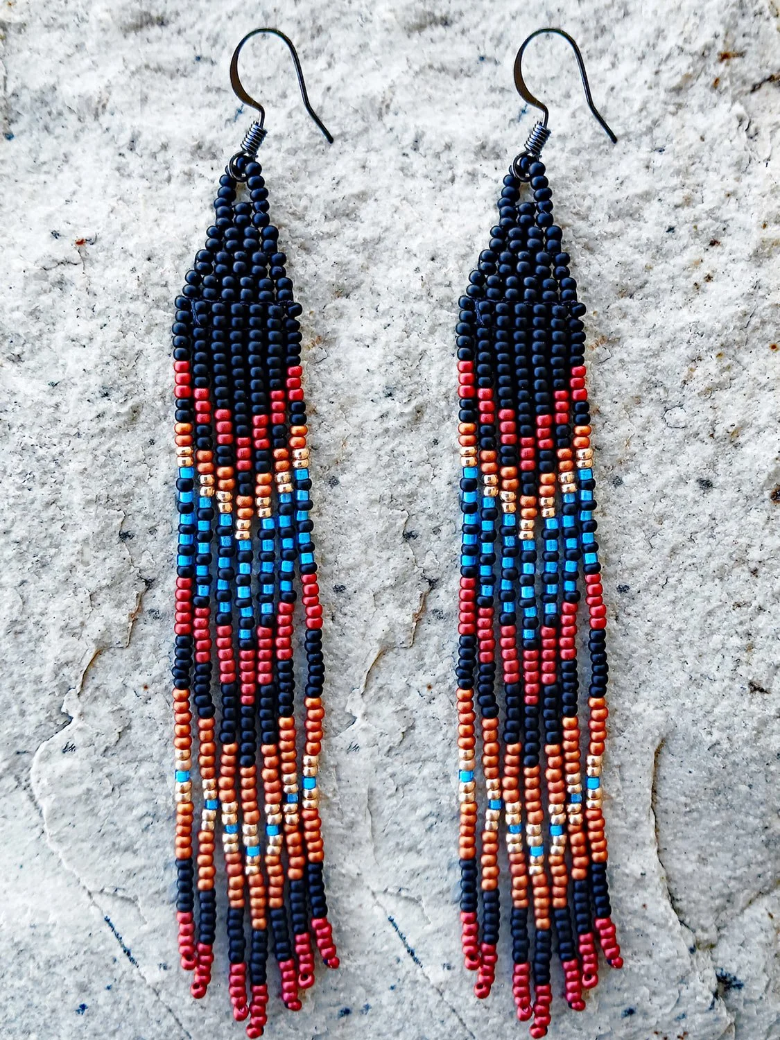 Handmade Southwestern beaded long fringe dangle earrings handwoven in a dramatic black, red, blue, gold, and copper mountain sunset color palette.