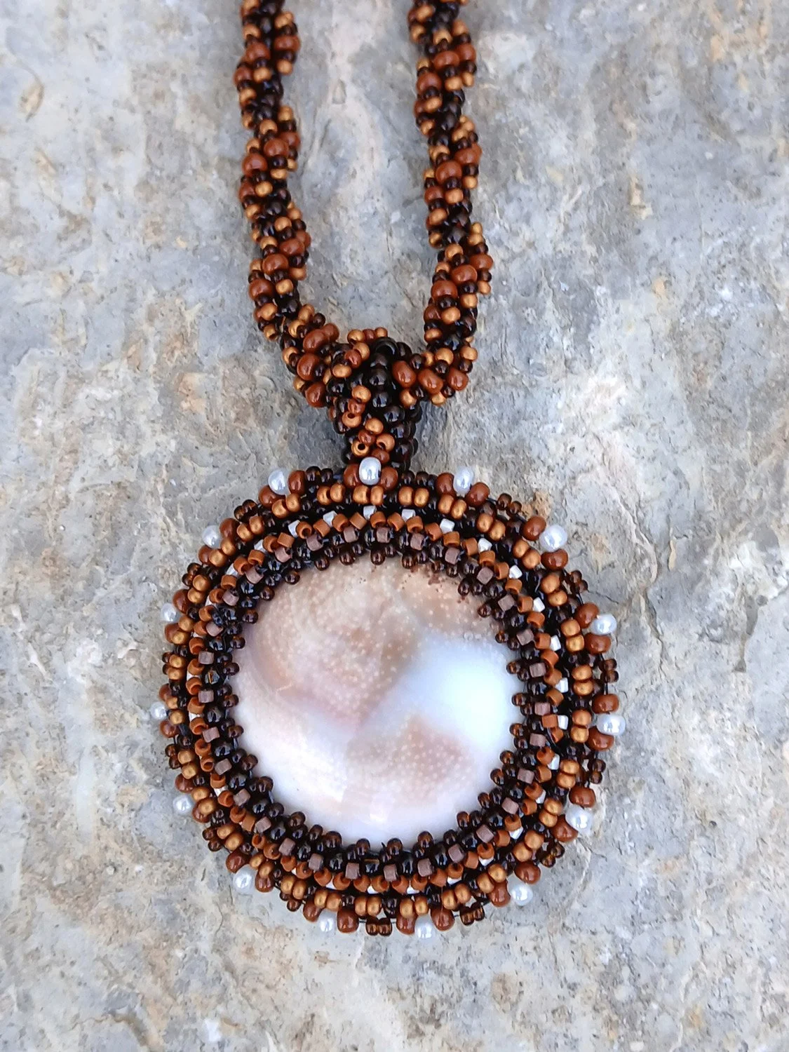 Handmade nature-inspired beaded necklace featuring a beaded bezel on natural spiral Shiva snail shell pendant handwoven in brown and white seed beads.