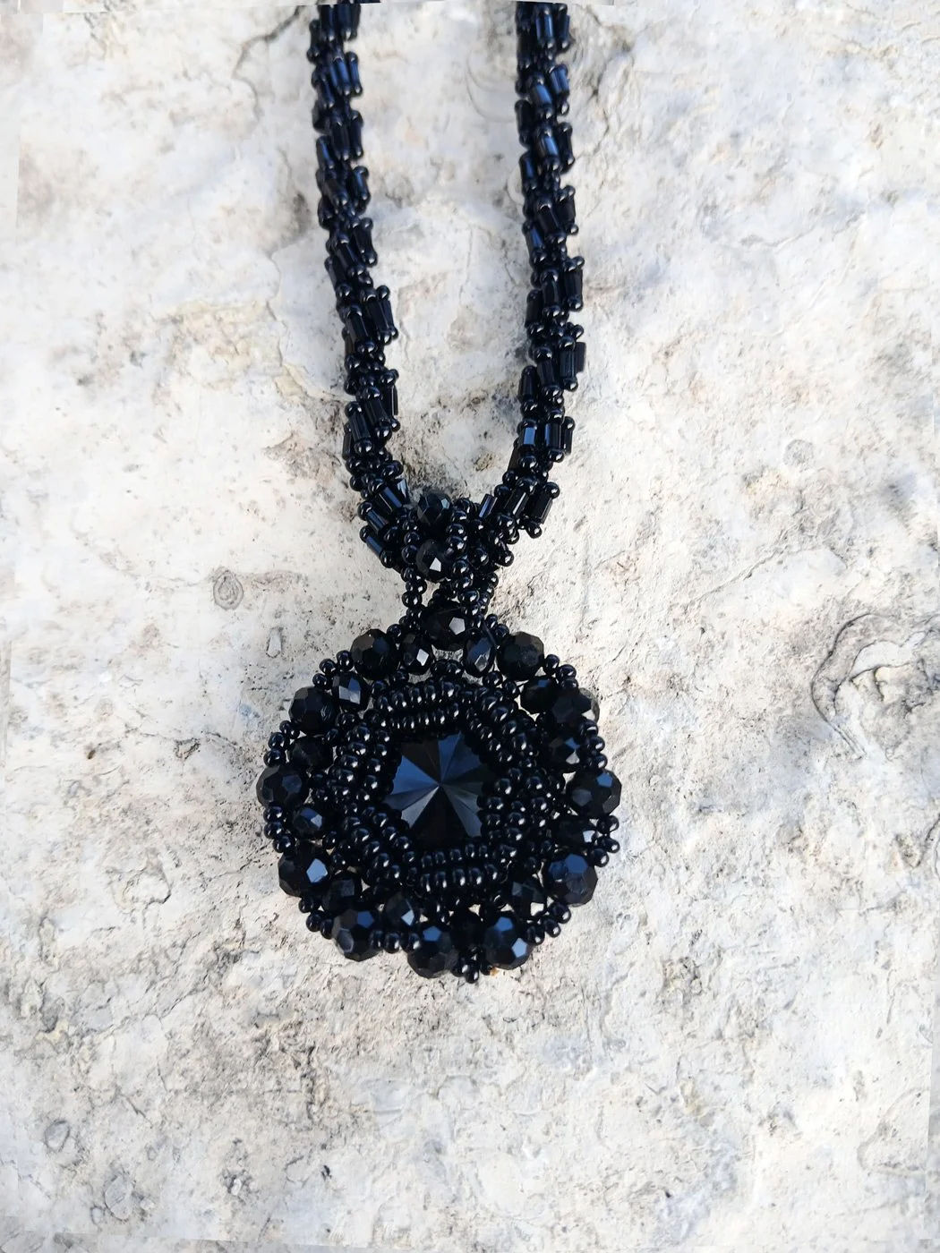Handmade statement pendant necklace featuring a sparkling black Rivoli crystal focal point handwoven with a matching seed bead chain.